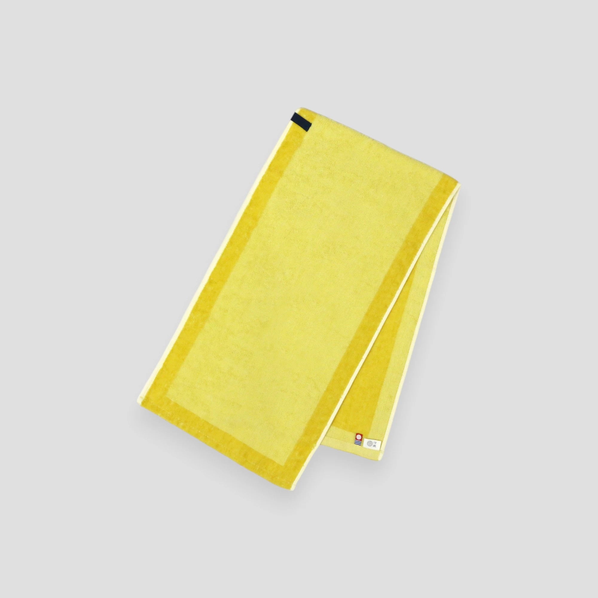 A folded yellow Imabari towel, showing the brand label and a hanging loop