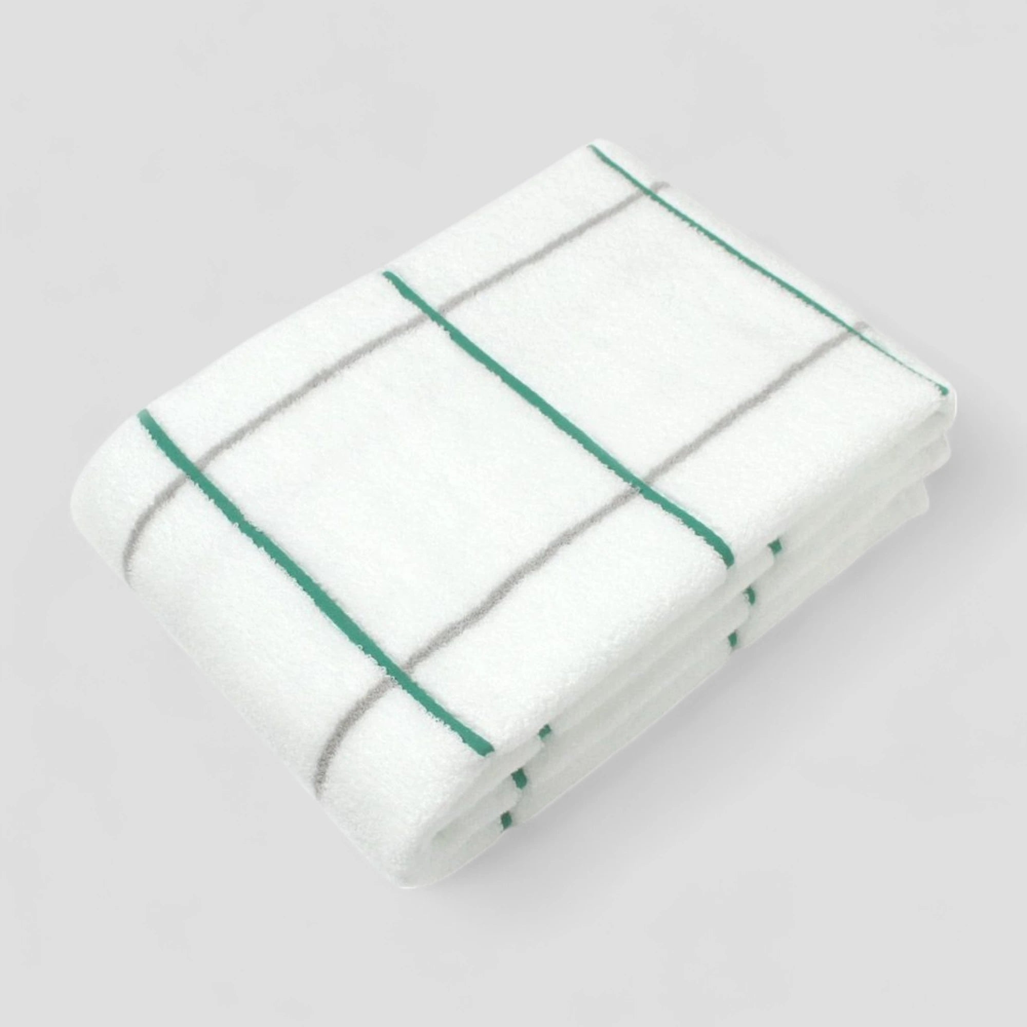 Folded white Imabari towel with green stripes on a light gray background