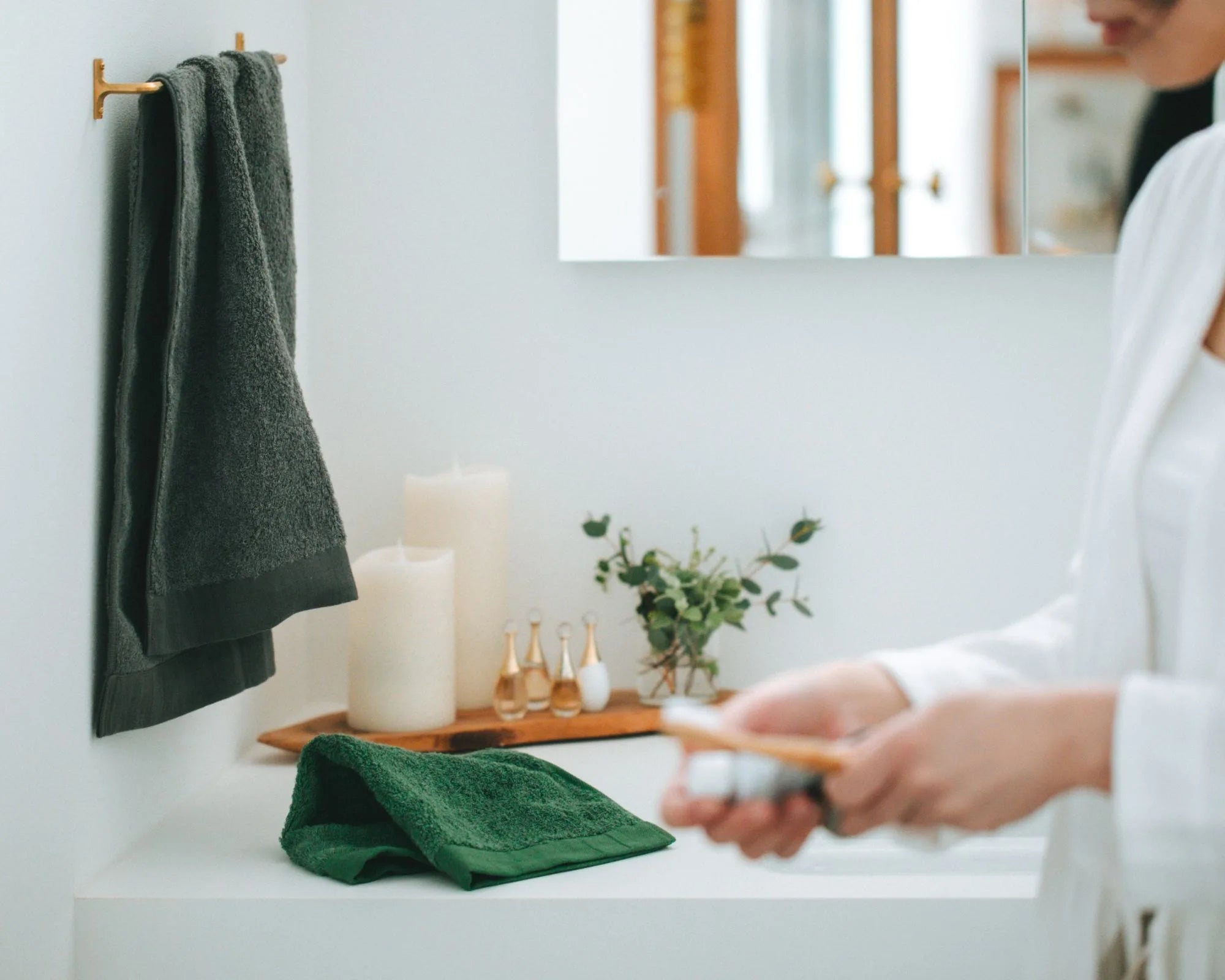 Person cleaning a surface with a green Imabari towel in a bathroom setting.