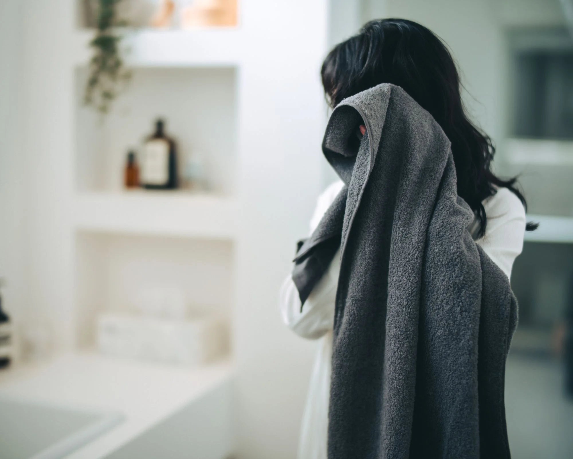 Person holding a gray Imabari towel in a bathroom setting