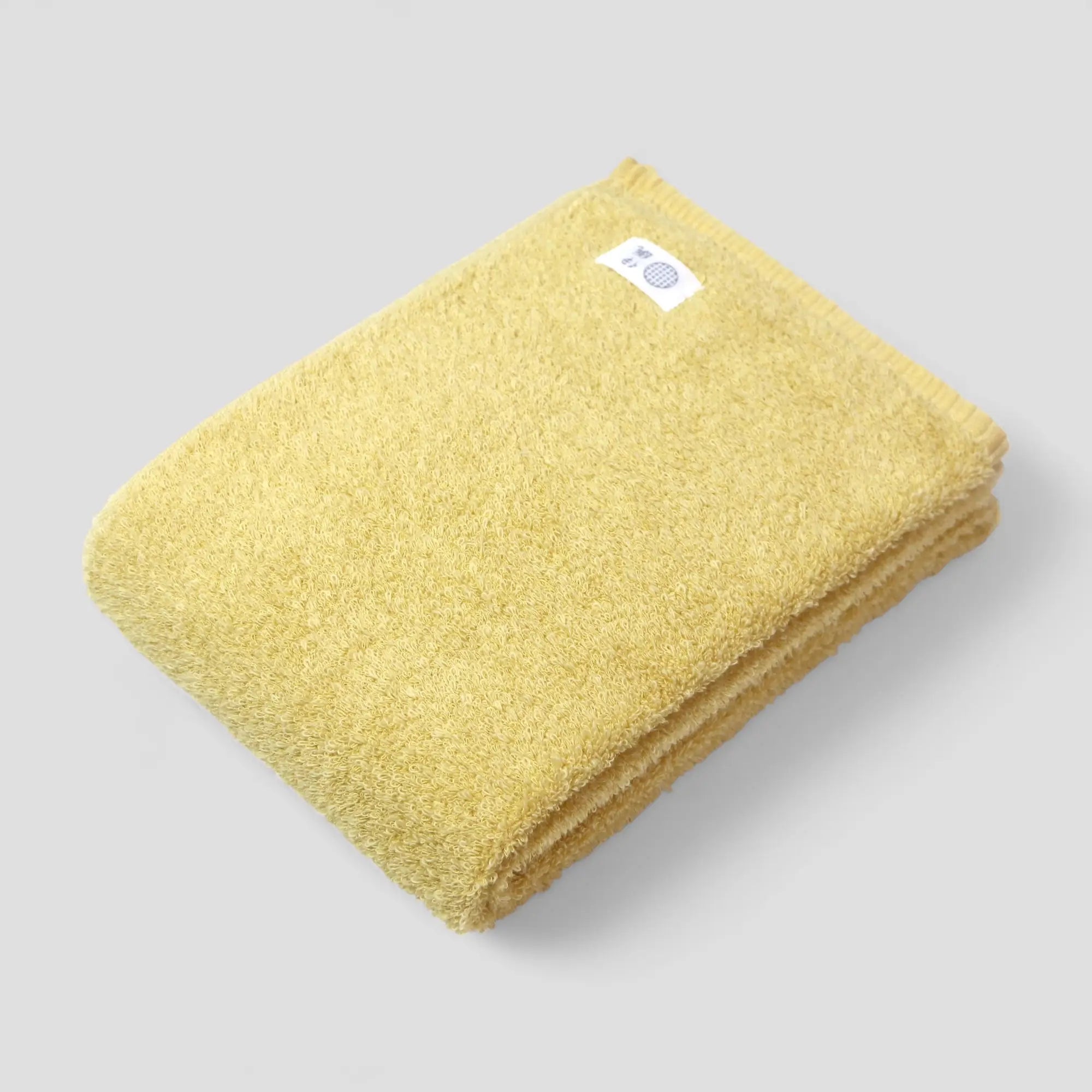 Folded yellow Imabari towel with a label on a gray background