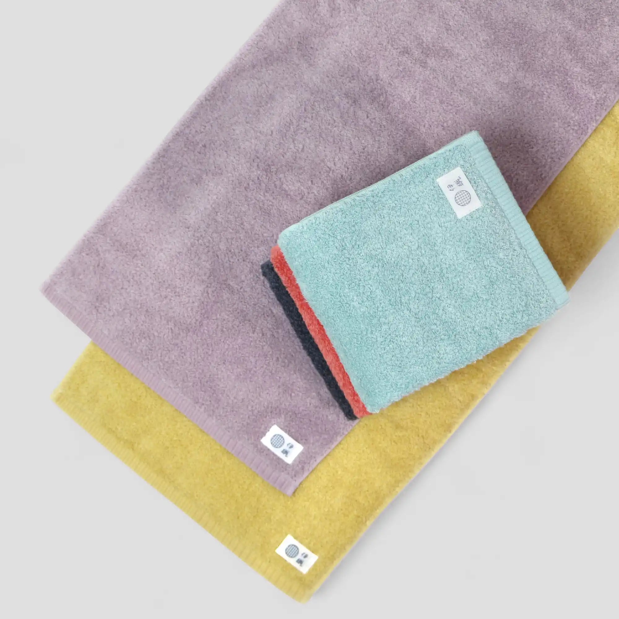 Set of five Imabari towels in purple, ink-blue, red,light-blue, and yellow on a light gray background