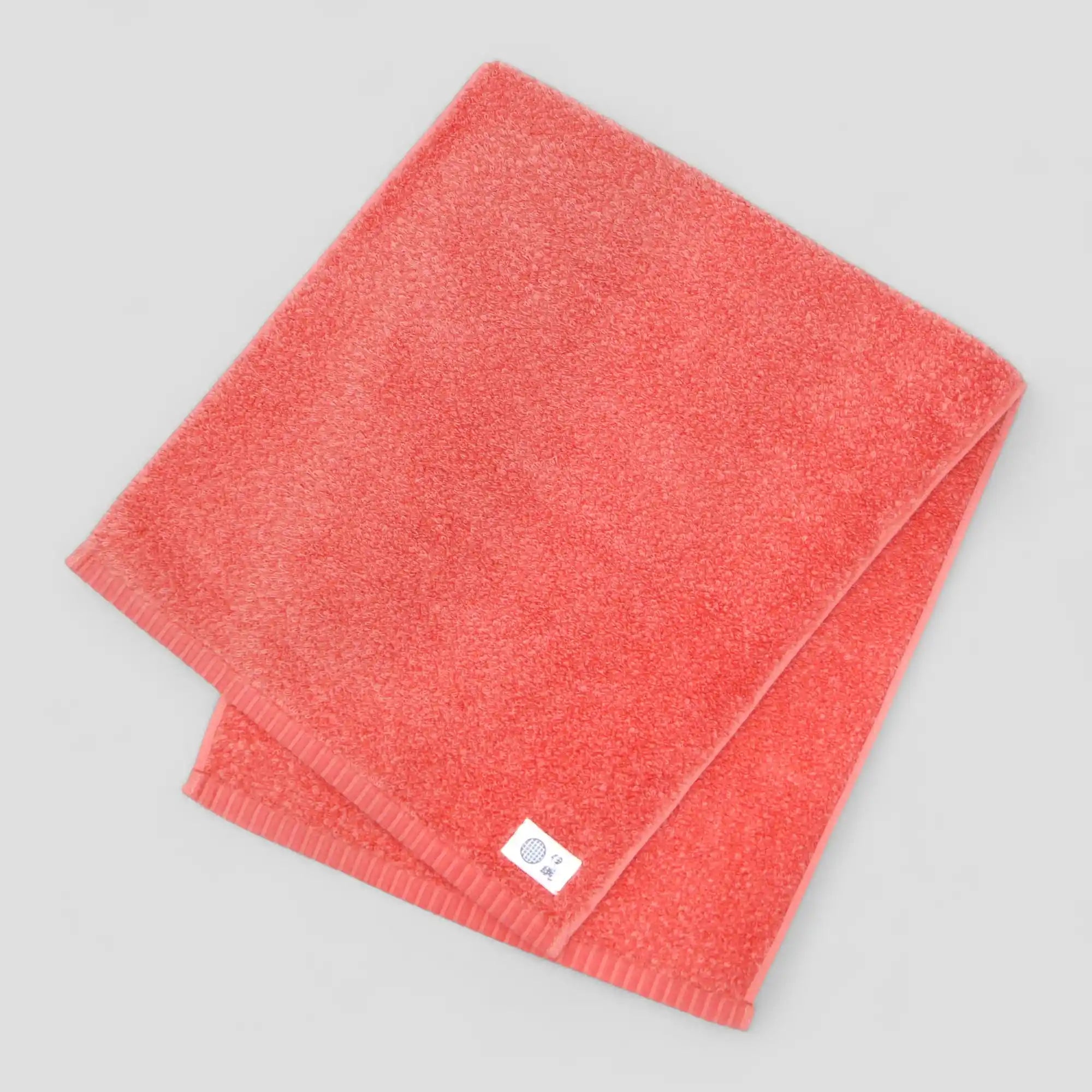 Folded red Imabari towel with a label on a gray background