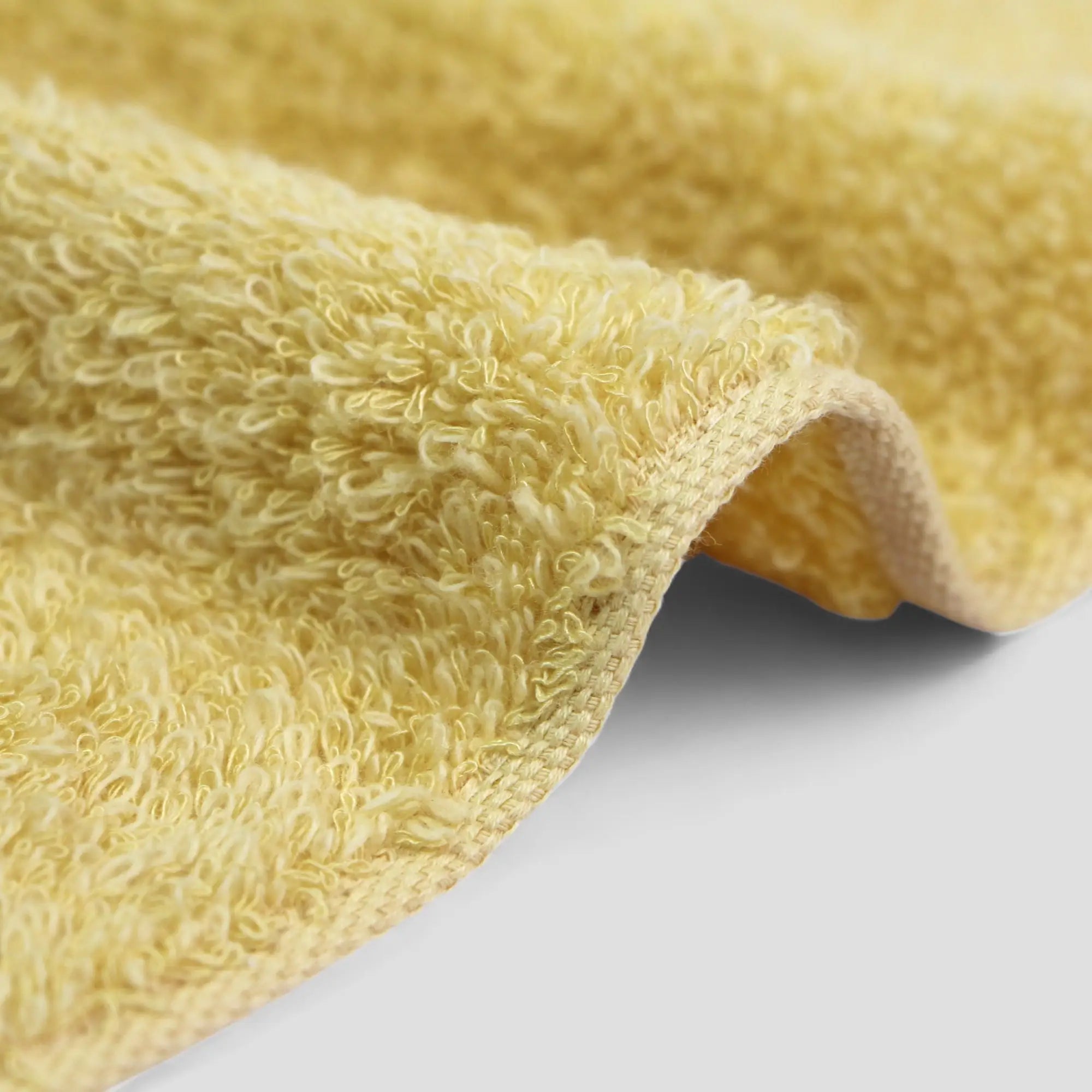 Close-up of a textured yellow Imabari towel fabric on a light gray background