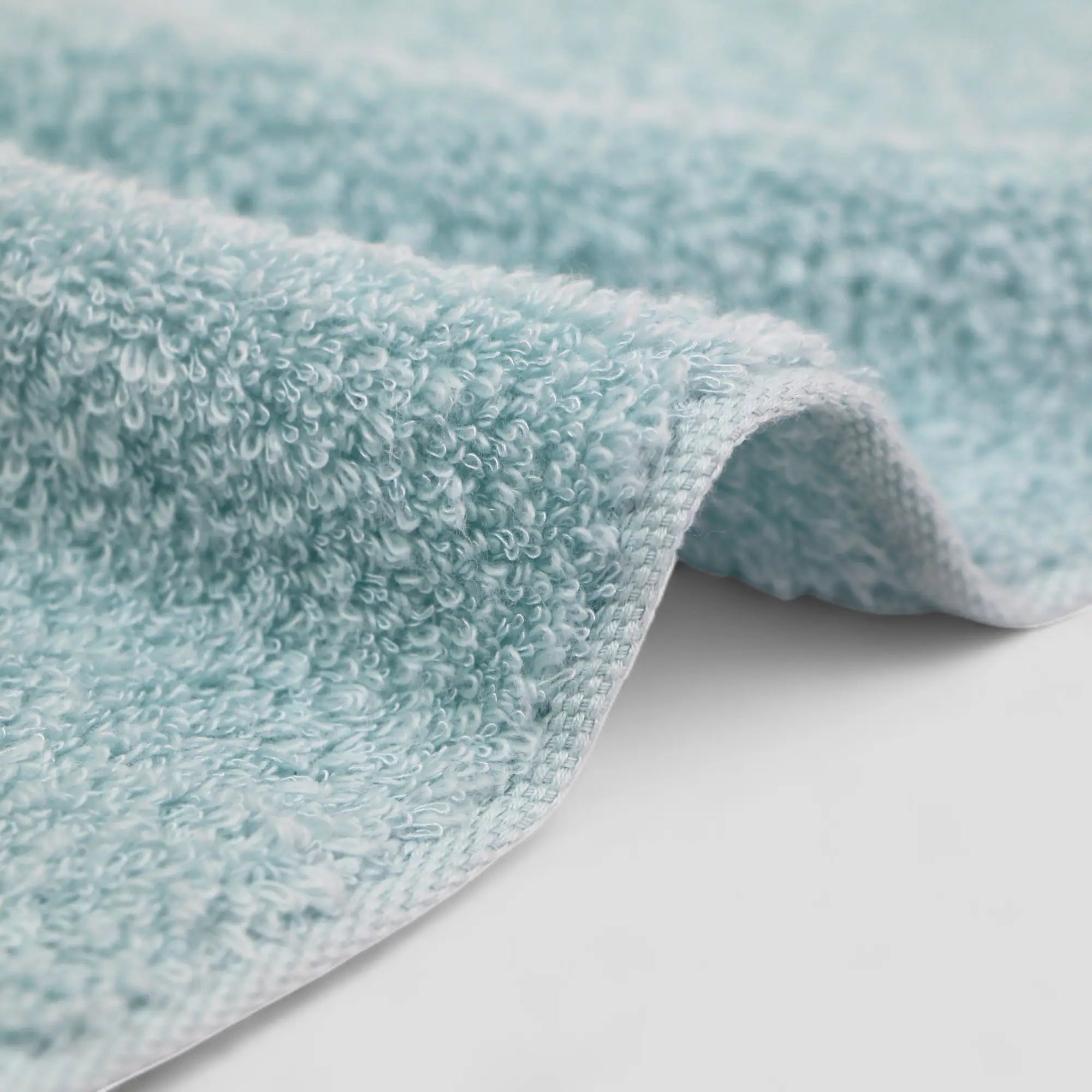 Close-up of a textured light blue Imabari towel on a white surface