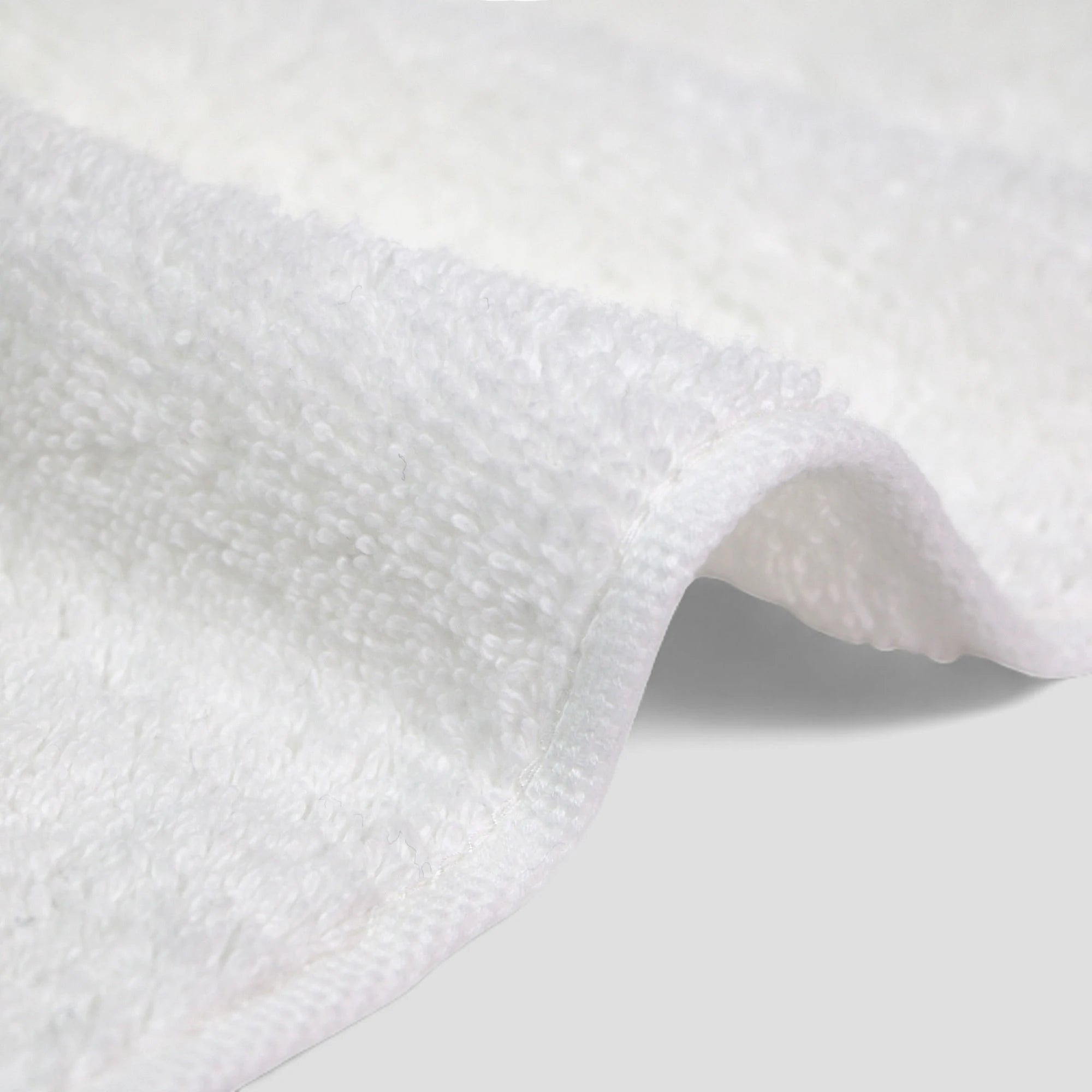 Close-up of white textured Imabari towel fabric on a light gray background