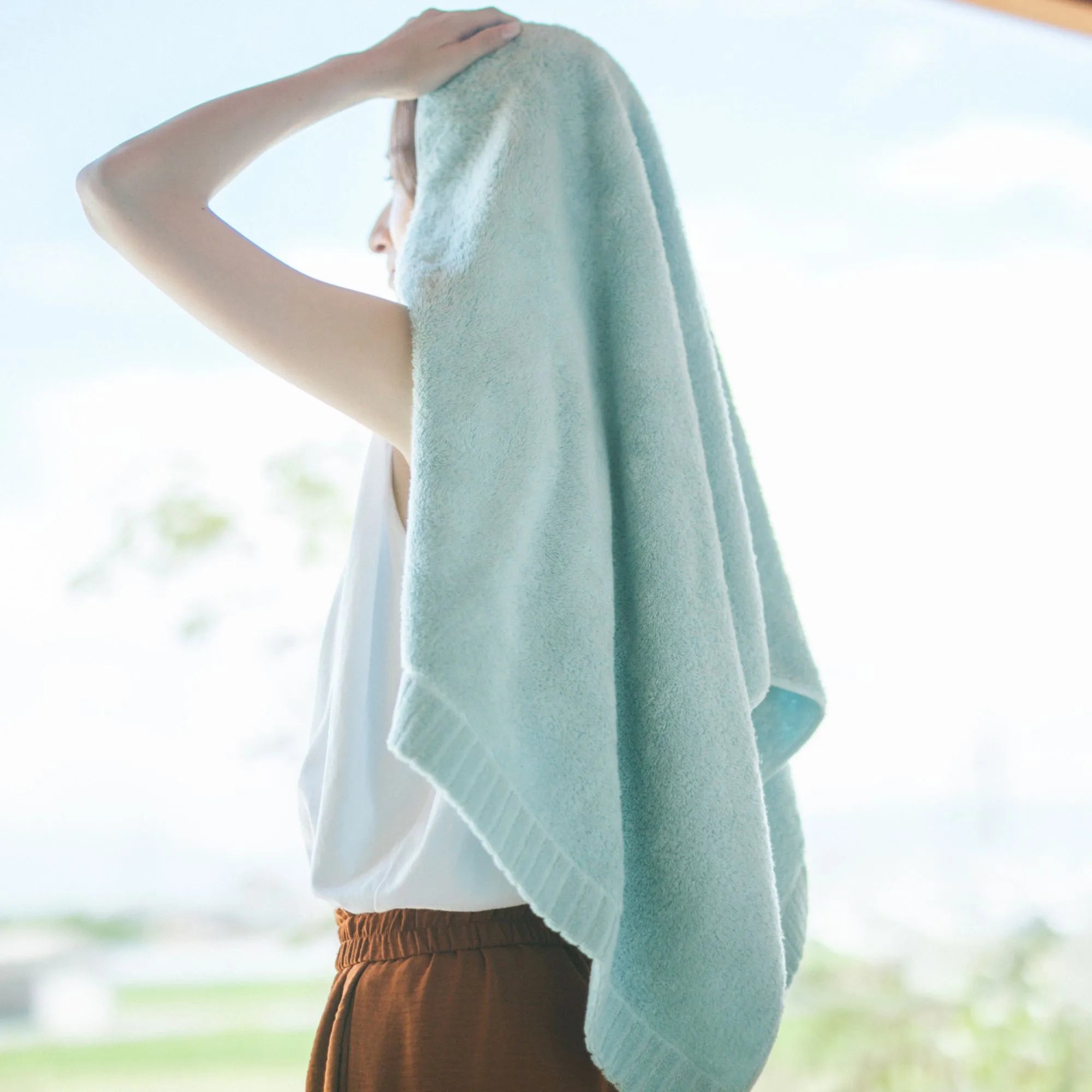 Person wearing a light blue Imabari towel with a blurred outdoor background