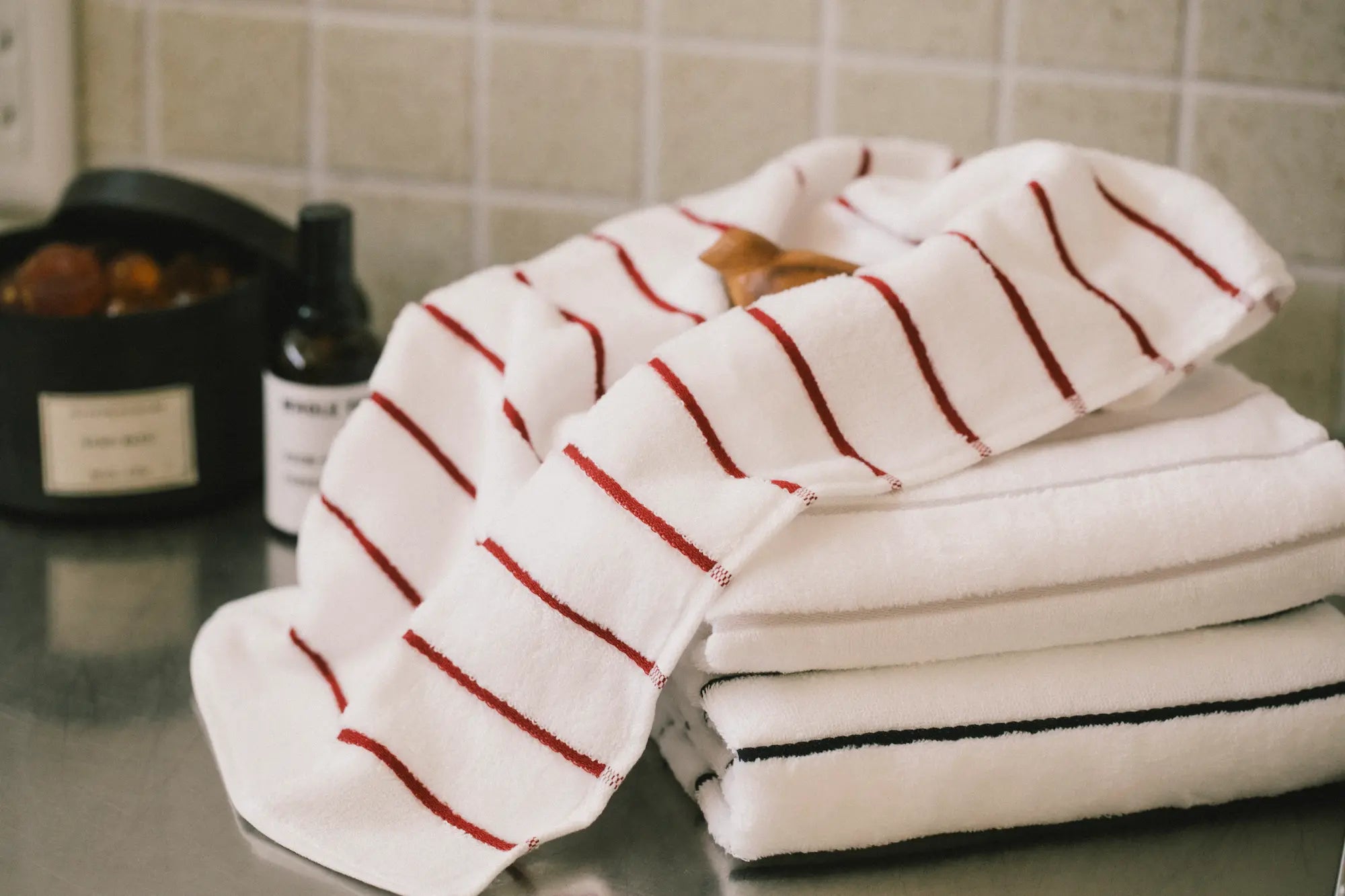 A stack of folded white Imabari towels with red, gray and navy stripes on the bath room