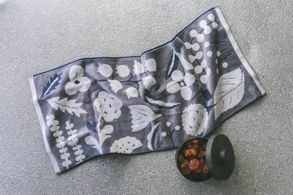 Left a gray Imabari towel with white floral pattern on the stone table