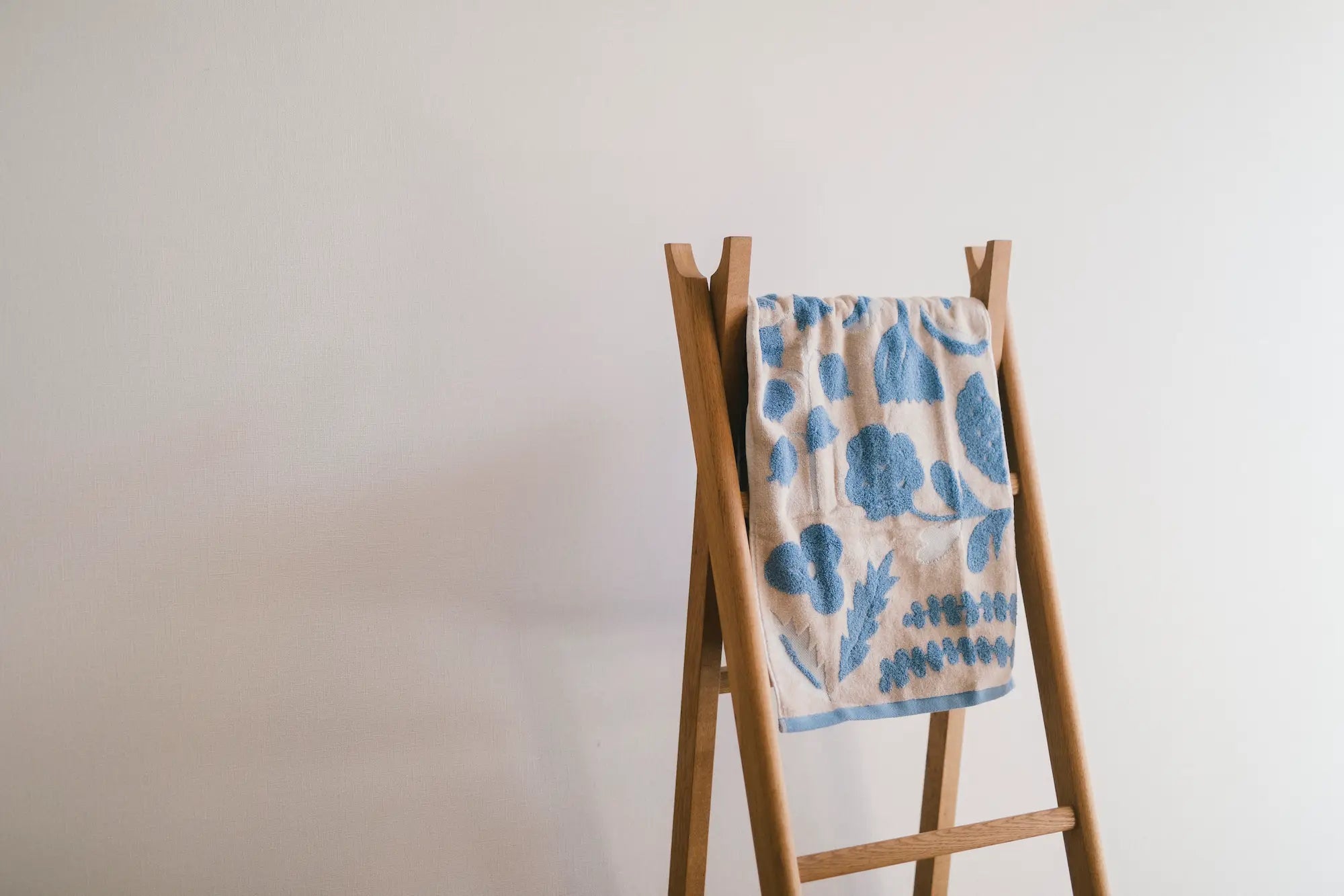 Hang a beige floral Imabari towel on the wooden bar