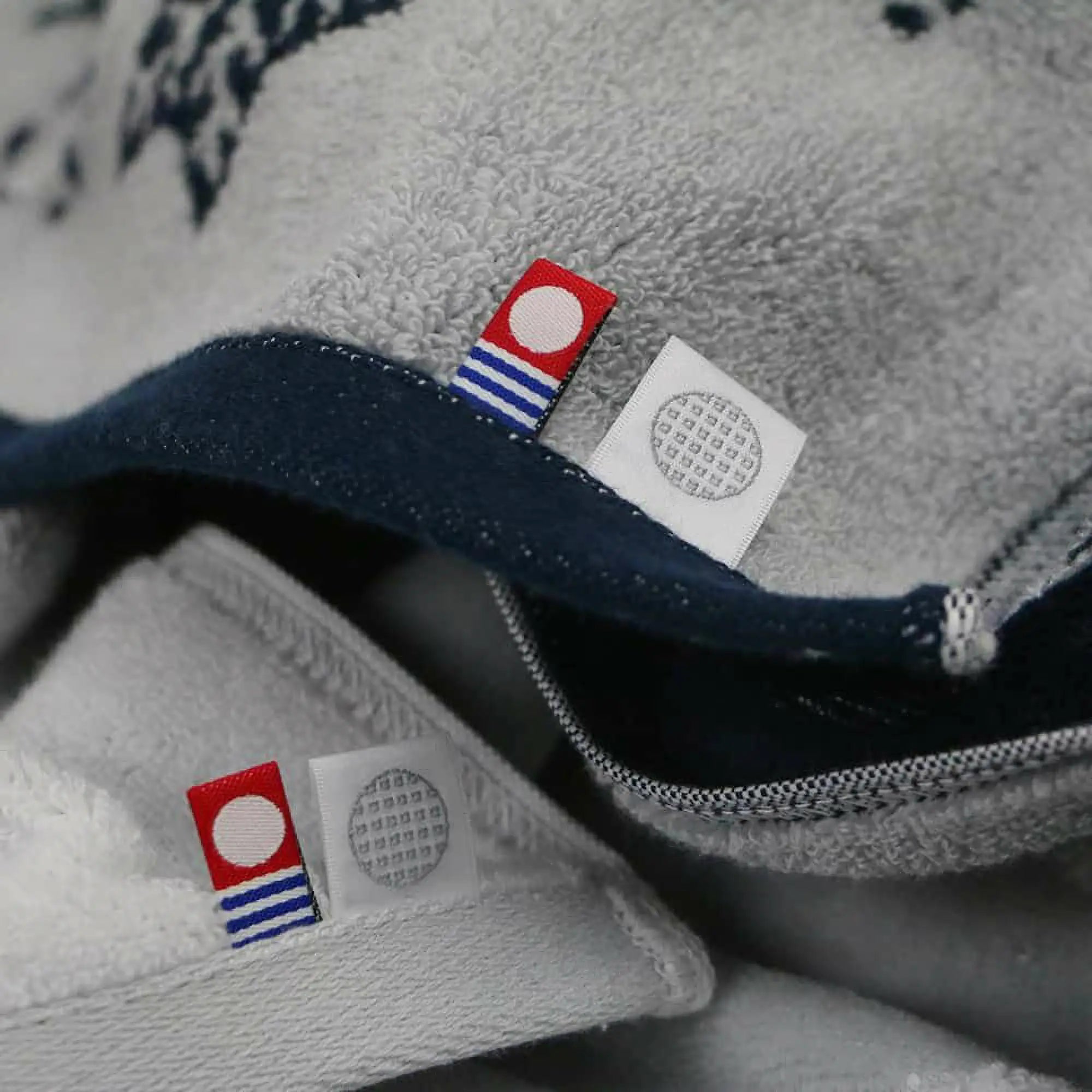 Close-up of fabric with Imabari towel brand labels on a gray and navy background