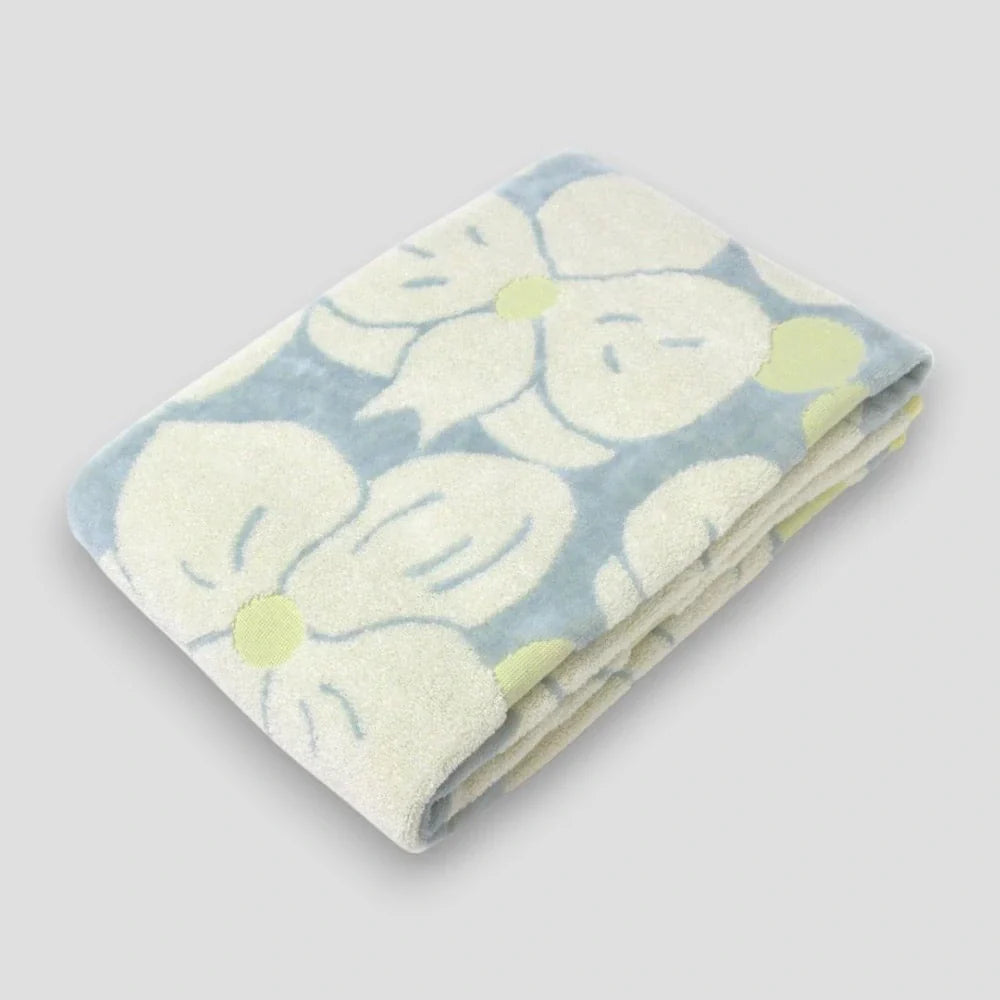 Folded Imabari towels with a jacquard weave featuring a  white phalaenopsis orchid motif 