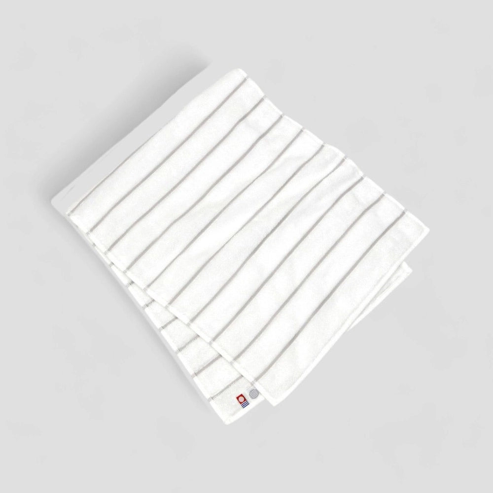 Folded white Imabari towel with gray stripe showing labels.