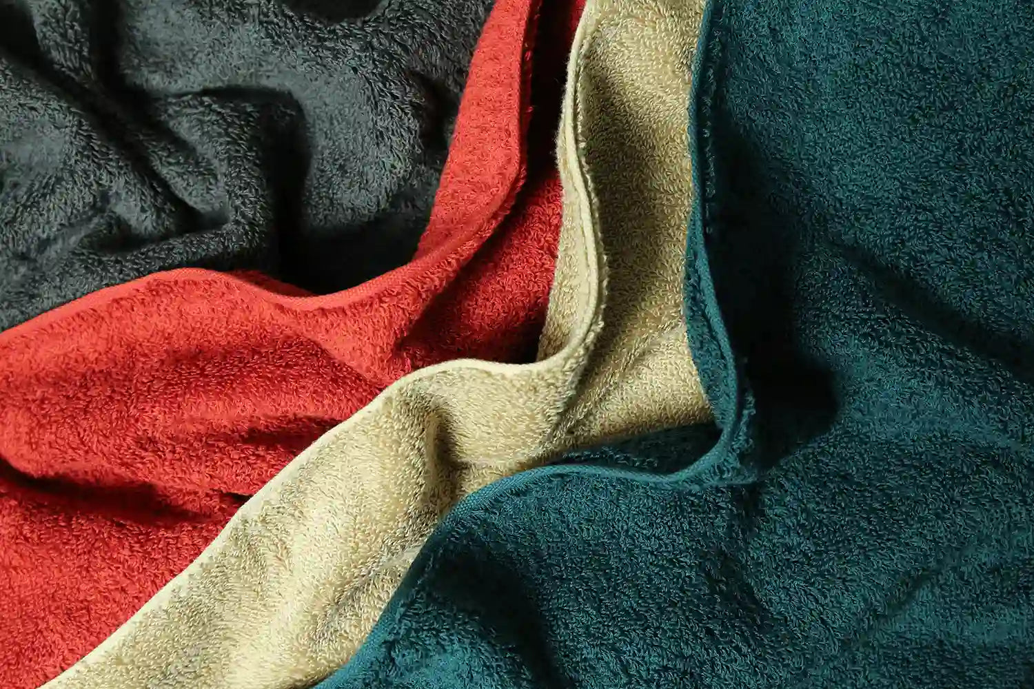 Close-up of a fabric of Imabari towels in various colors including green, beige, red, and gray, made of cotton.