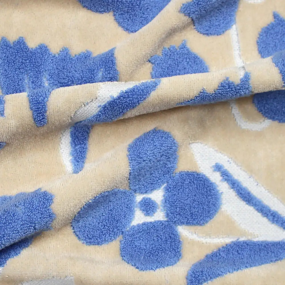 Close-up of a beige Imabari towel with a  jacquard blue floral pattern 