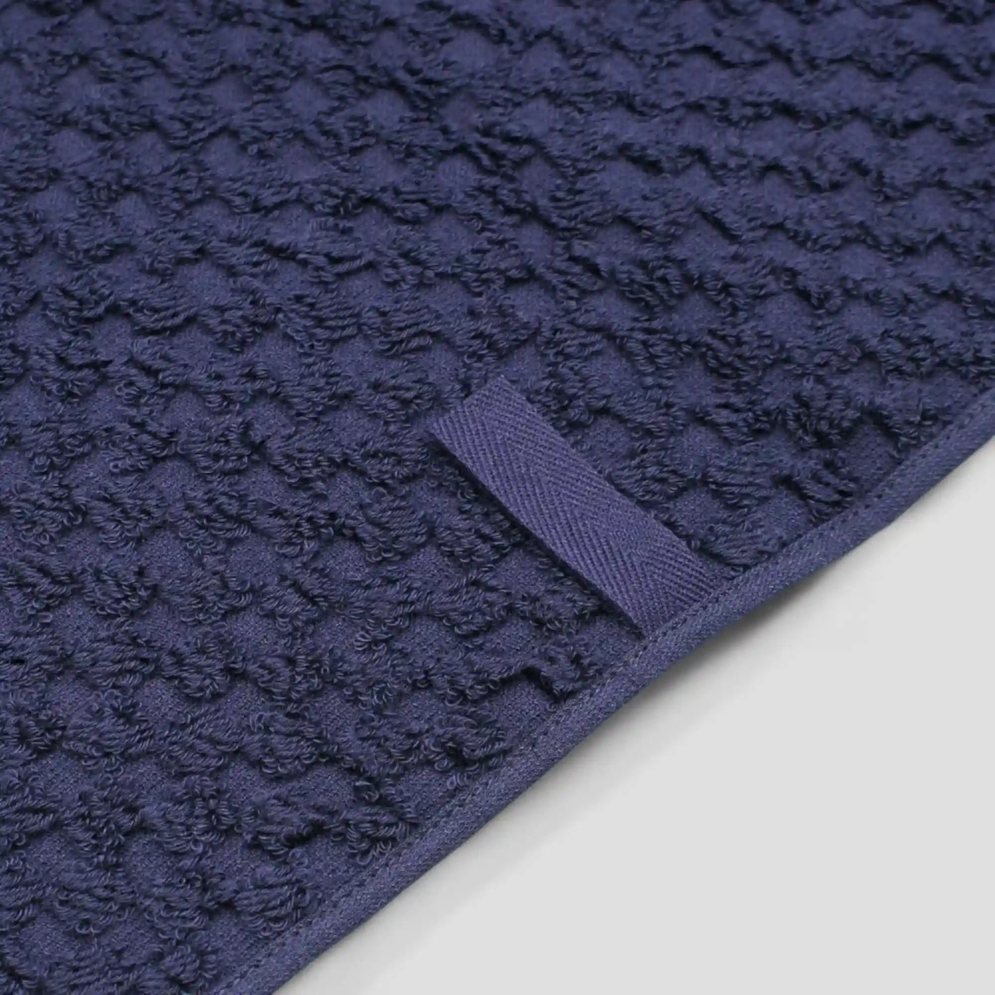 Close-up navy jacquard weave Imabari towel with a loop on a light gray background.