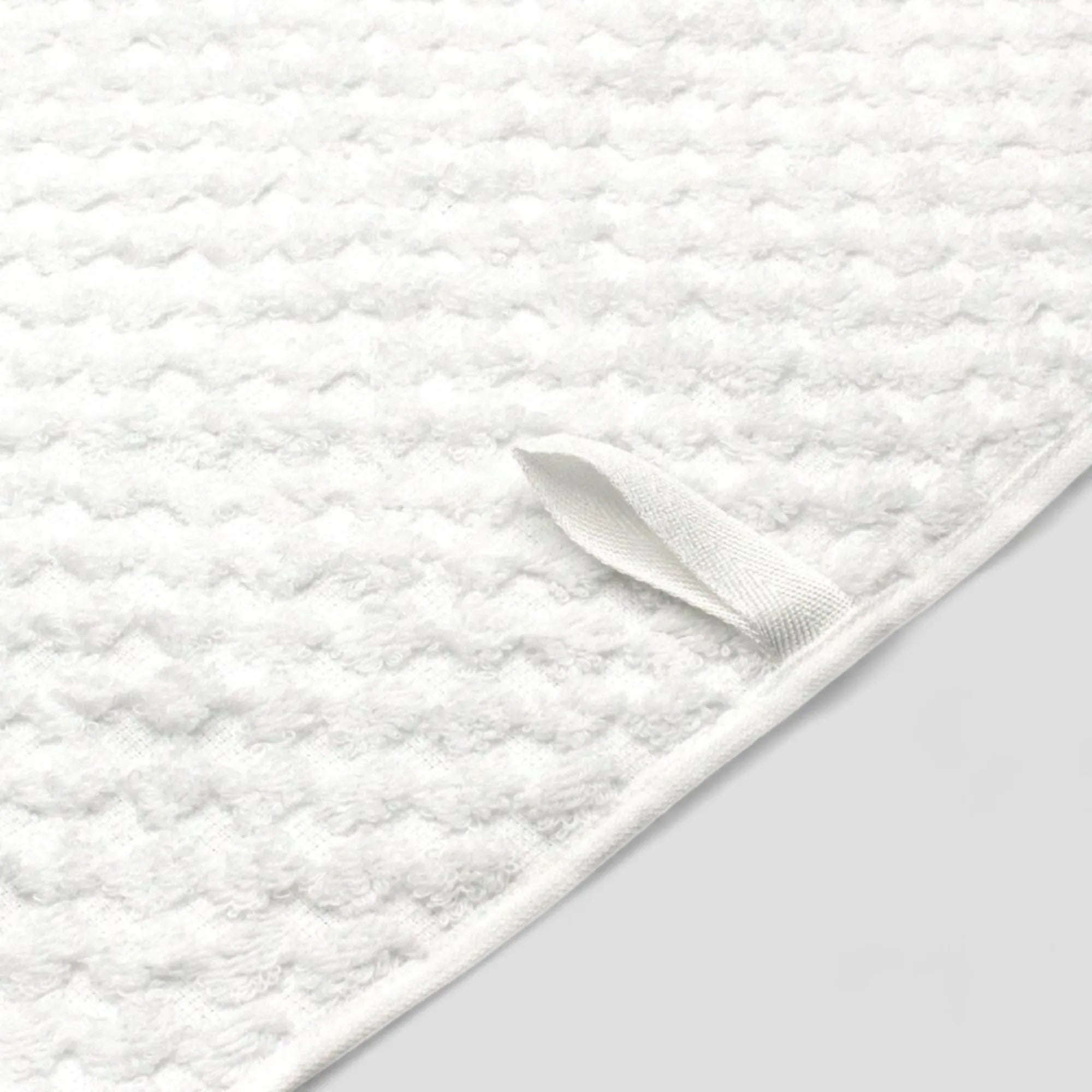 Close-up white jacquard weave Imabari towel with a loop on a light gray background.
