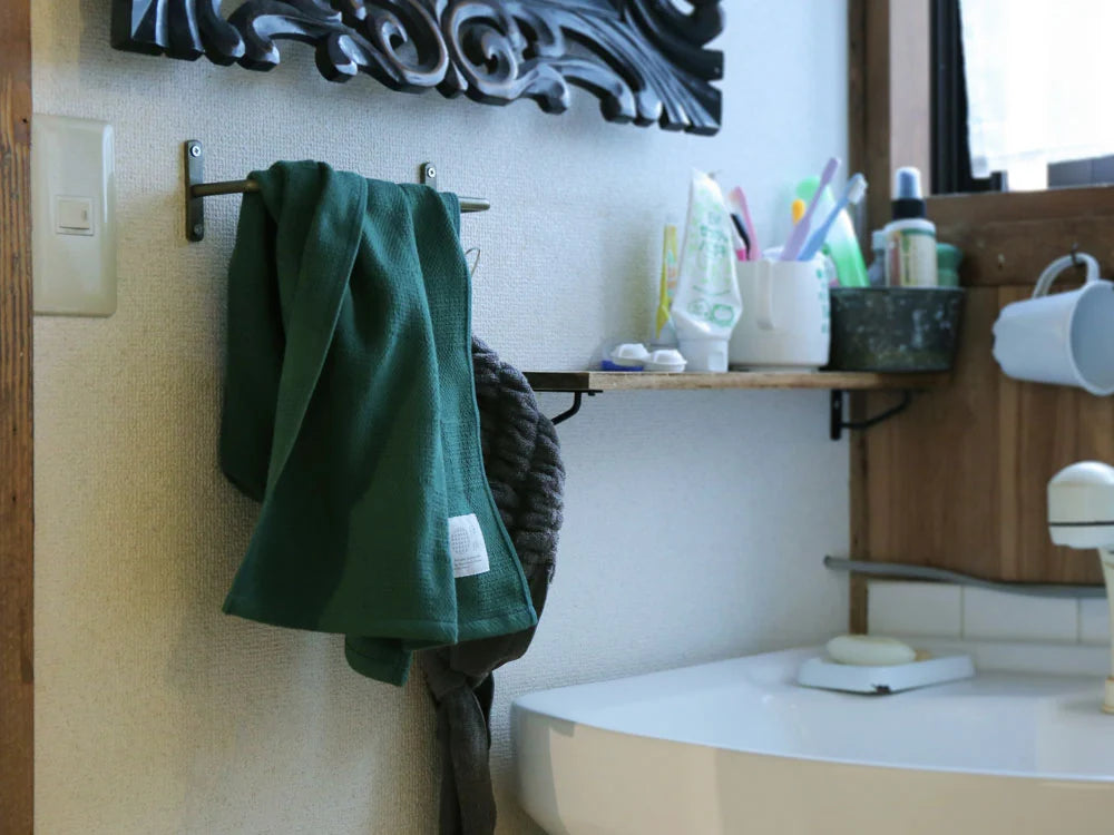 Hanging green "Non-Pile" Imabari towel in a bath room