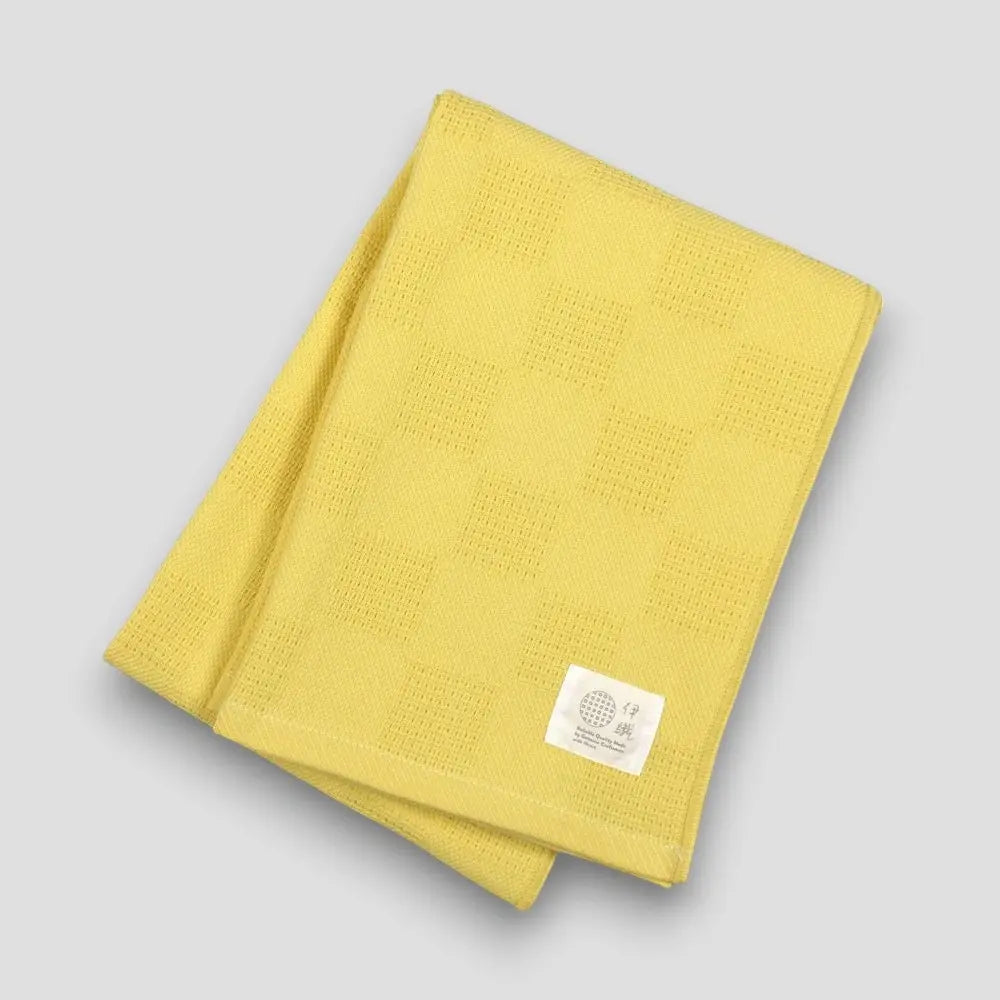 Folded yellow "Non-Pile" Imabari towel on a light gray background