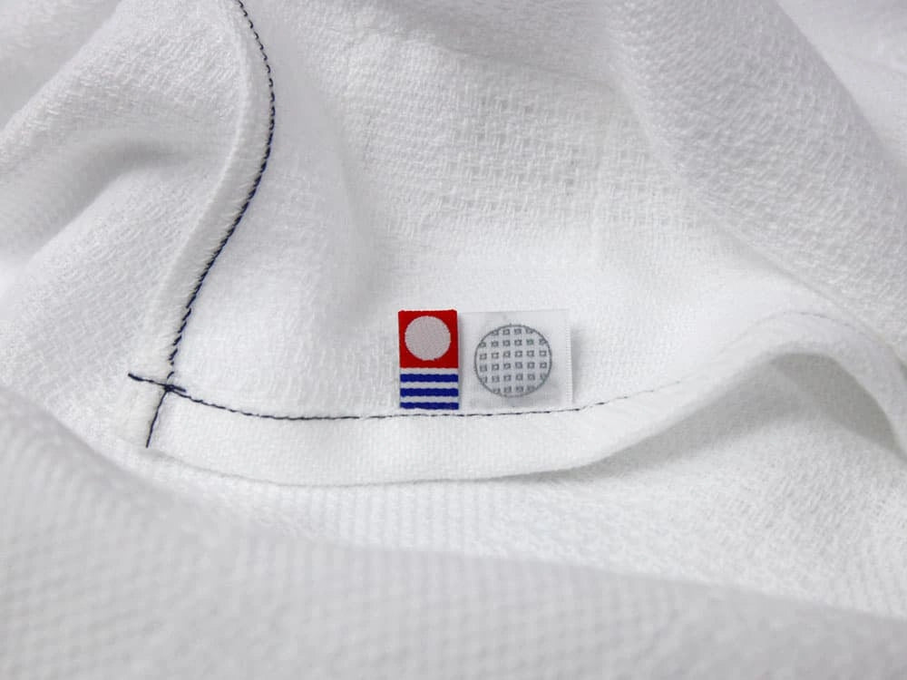 Close-up of "Non-Pile" white  Imabari
 towels with a Imabari mark tag on a backside