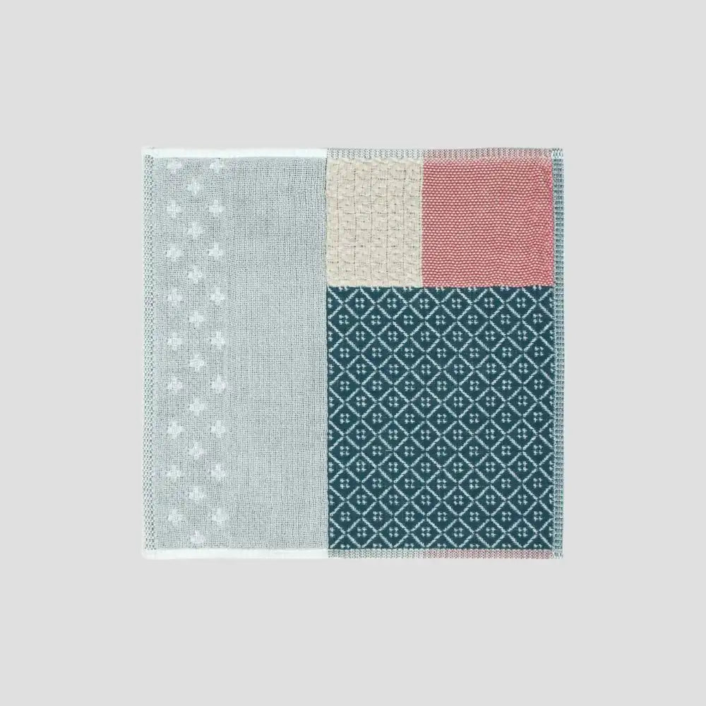 A  colorful patchwork design Imabari towel in various colors including red, navy and gray displayed against white background