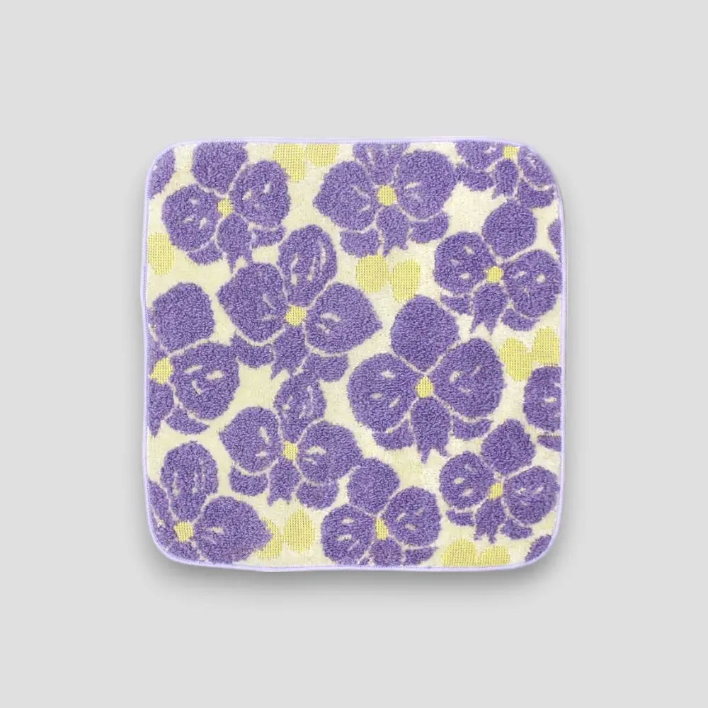 A small Imabari towel with purple floral flowers on the light gray background