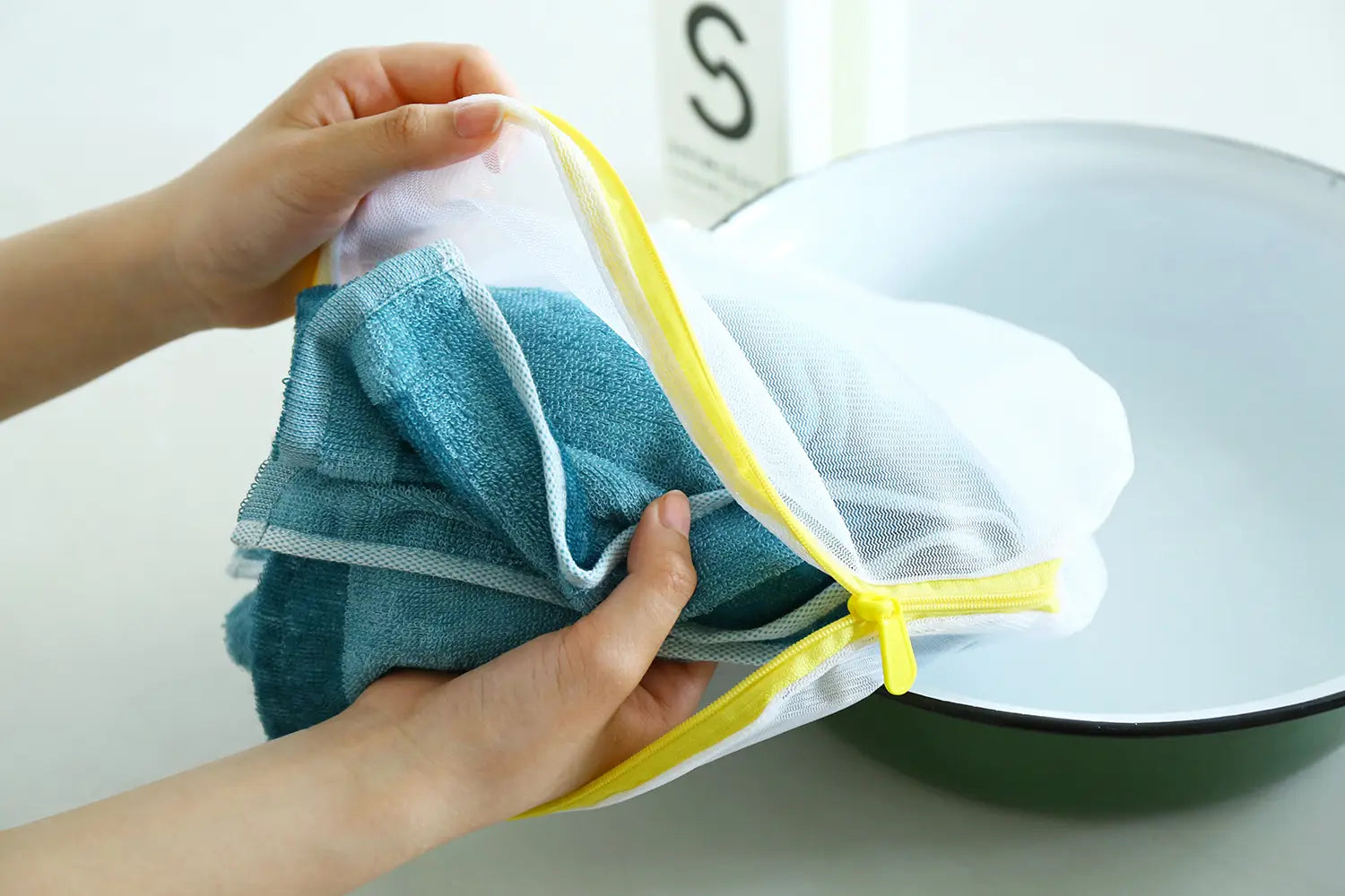 Putting a green Imabari towel into a laundry net