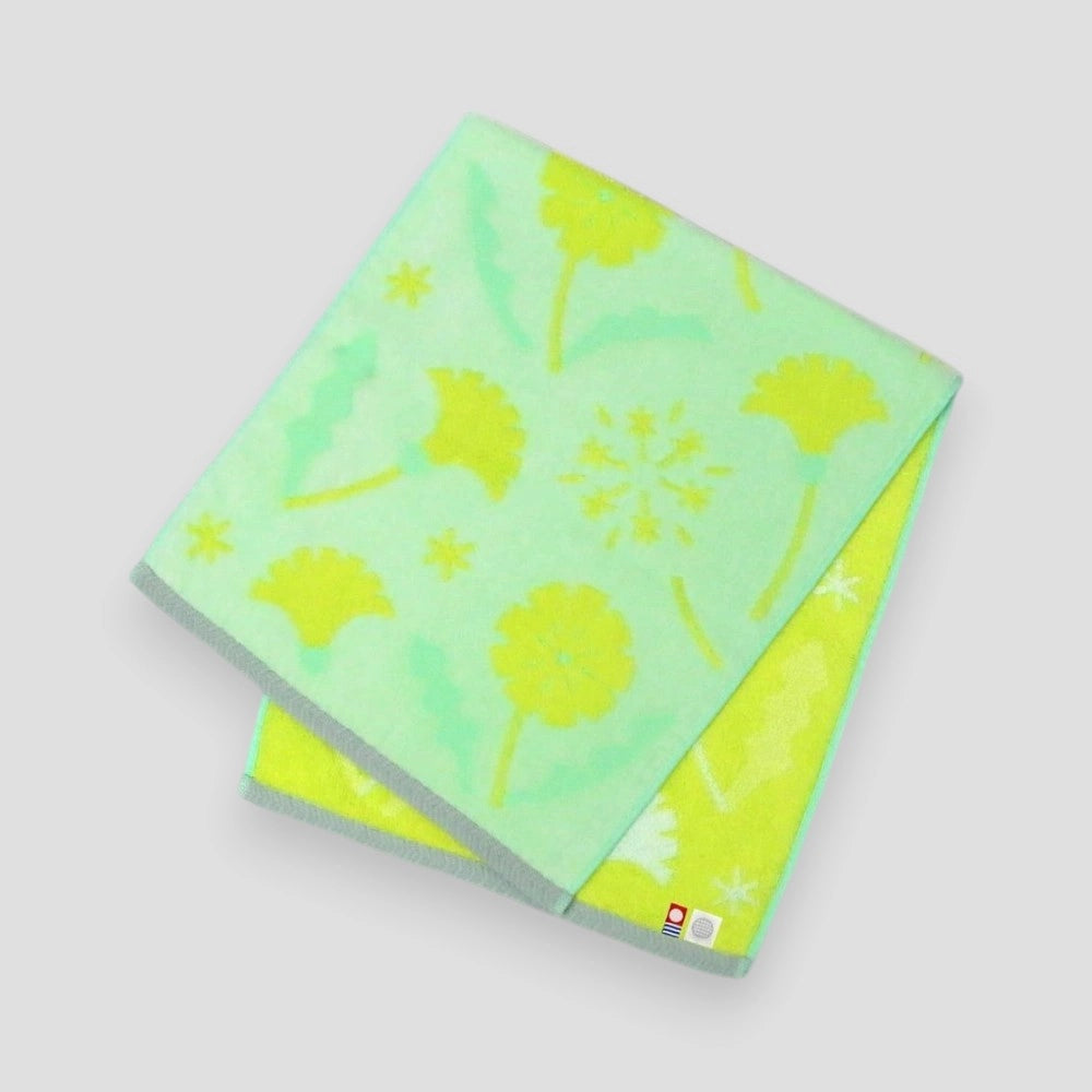 Folded Imabari towel in yellow with floral patterns, made from cotton, on a white background.