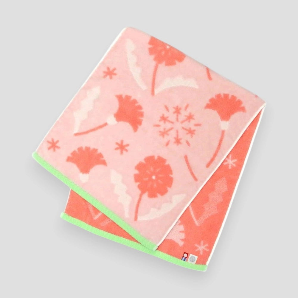 Folded Imabari towel in pink with floral patterns, made from cotton, on a white background.