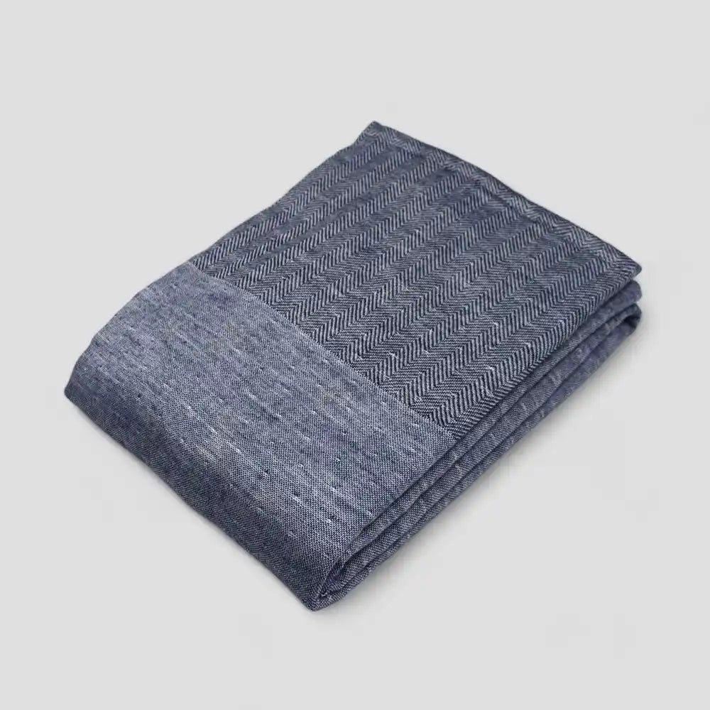 Folded navy Imabari towel with a subtle herringbone pattern on a light gray background.