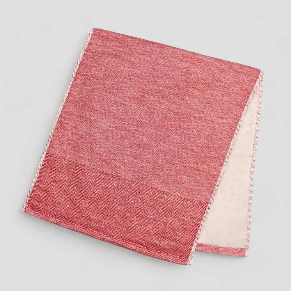 Folded red Imabari towel with a subtle herringbone pattern on a light gray background.