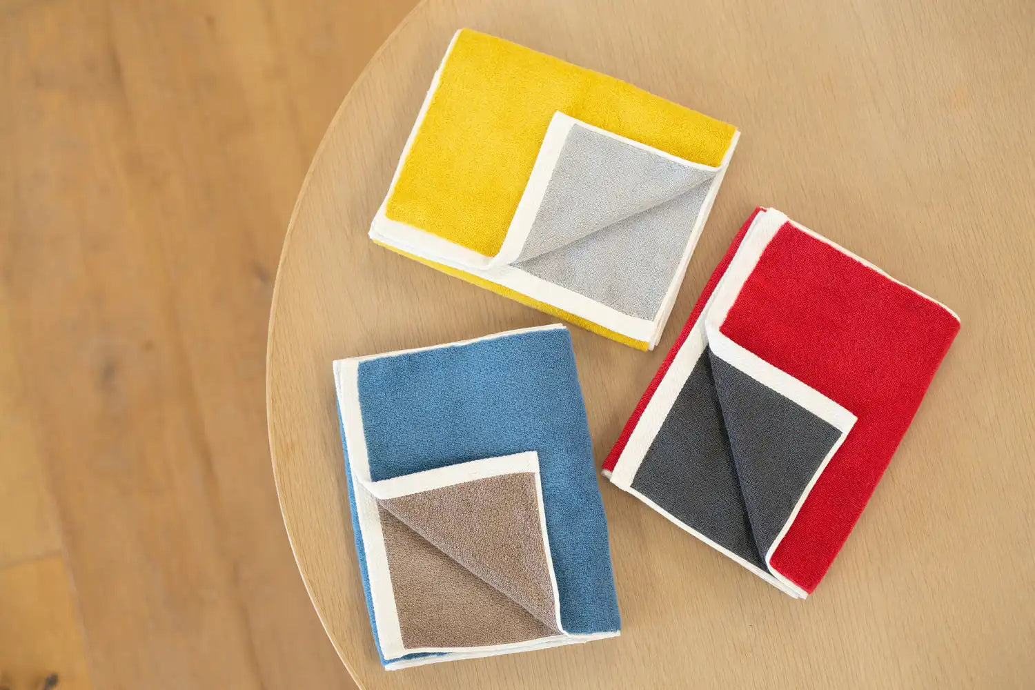 Three colors of reversible Imabari towels folded on a table