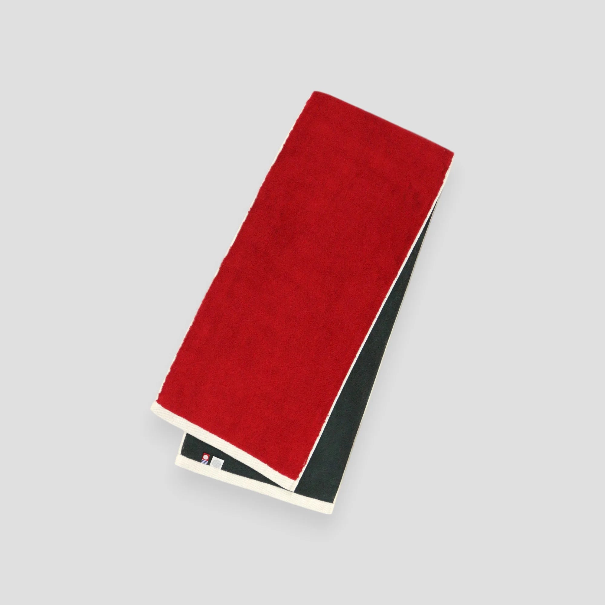 A folded red and gray reversible Imabari towel with the brand label visible