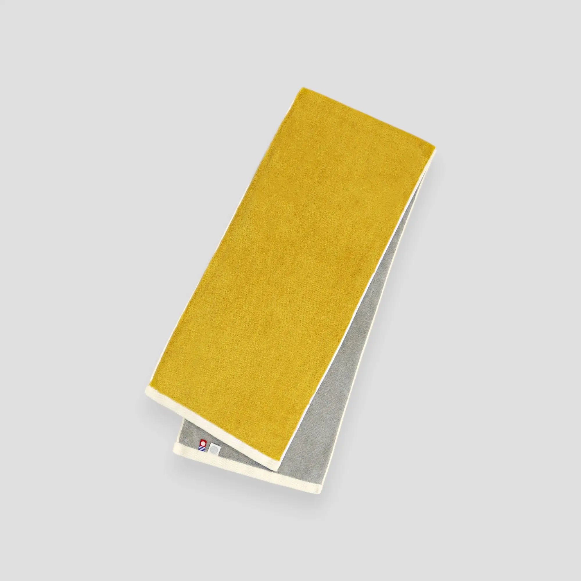 A folded yellow and gray reversible Imabari towel with the brand label visible