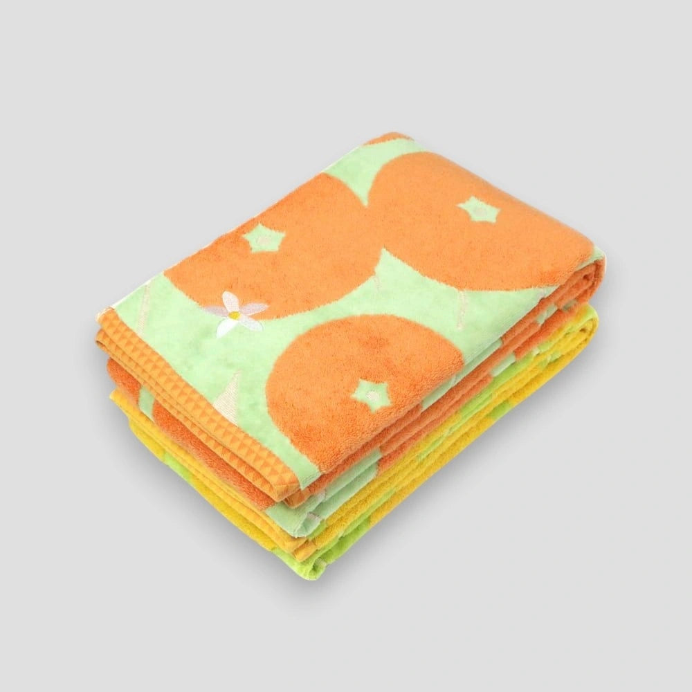 A stack of folded Imabari towels featuring a pattern with the Iyokan citrus fruit and green leaves on a white background