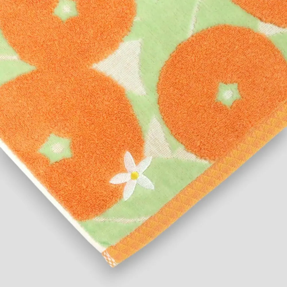 Close-up of a white flower embroidery in the colorful Imabari towel with orange  Iyokan pattern