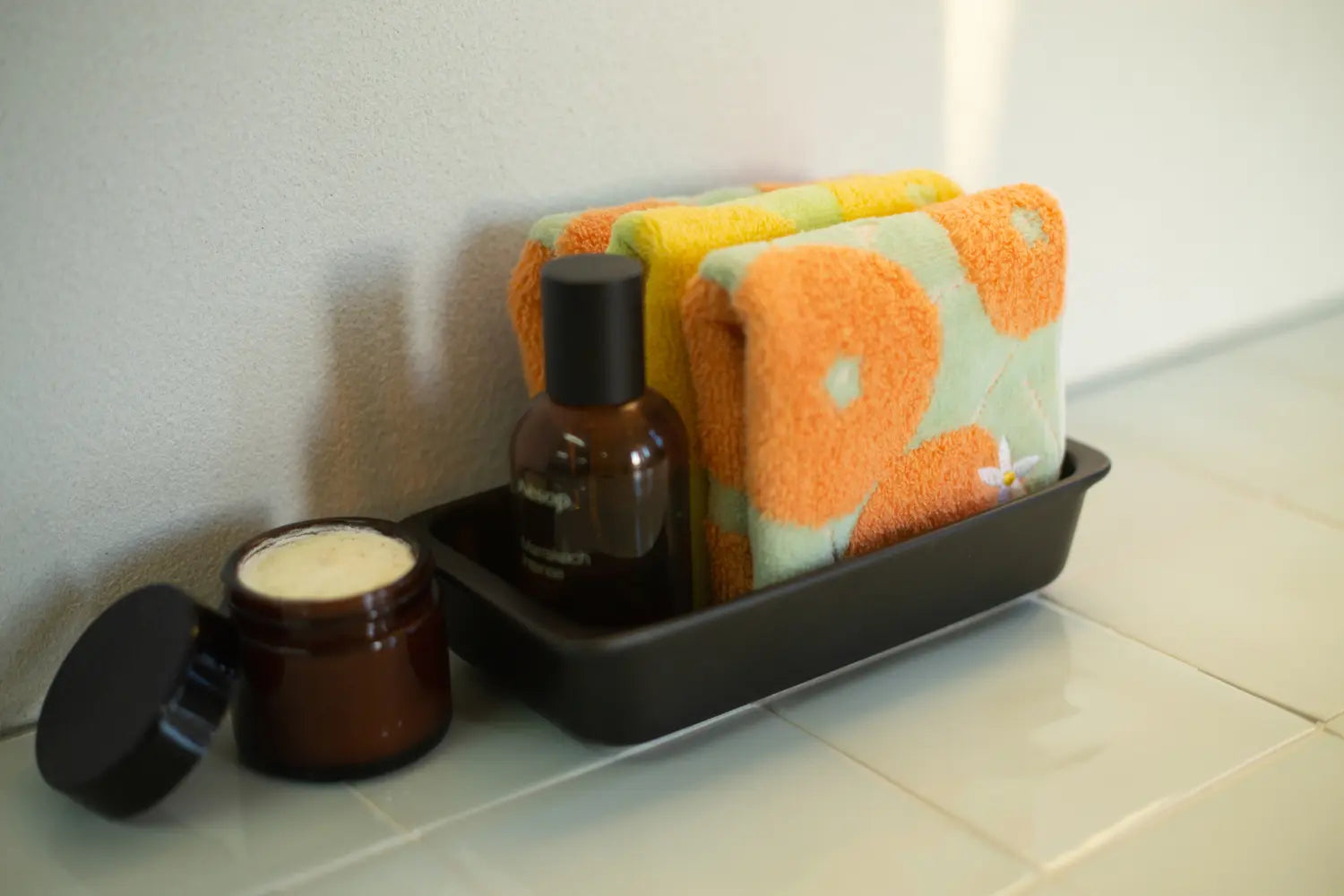 Stock of folded colorful Imabari towels with spray and cream jar in the bath room