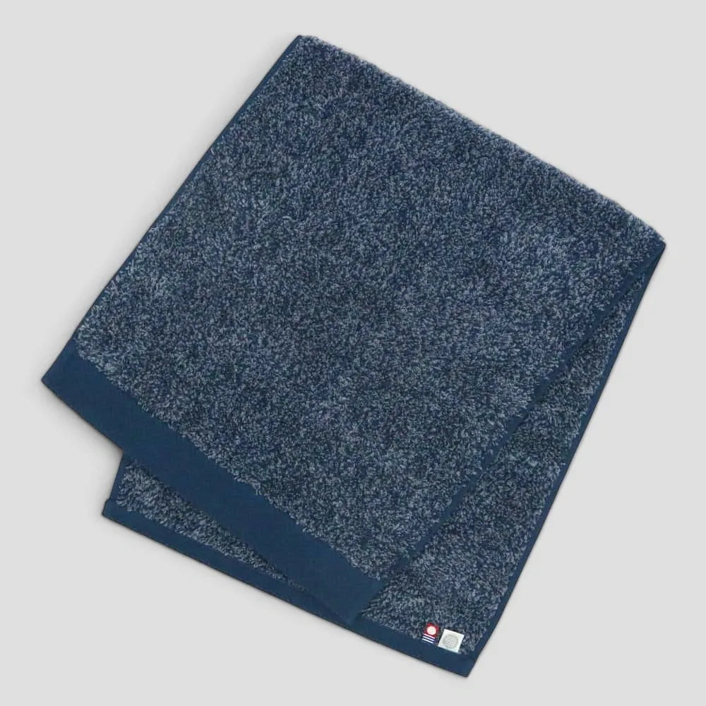 Folded navy Imabari towel with light gray background.