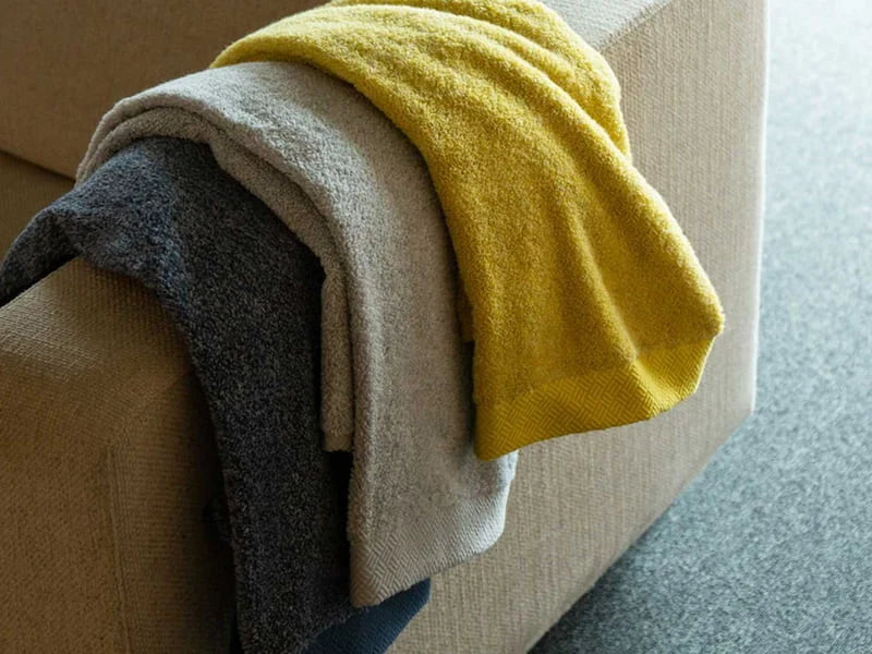Folded yellow, gray and navy Imabari towel on the couch