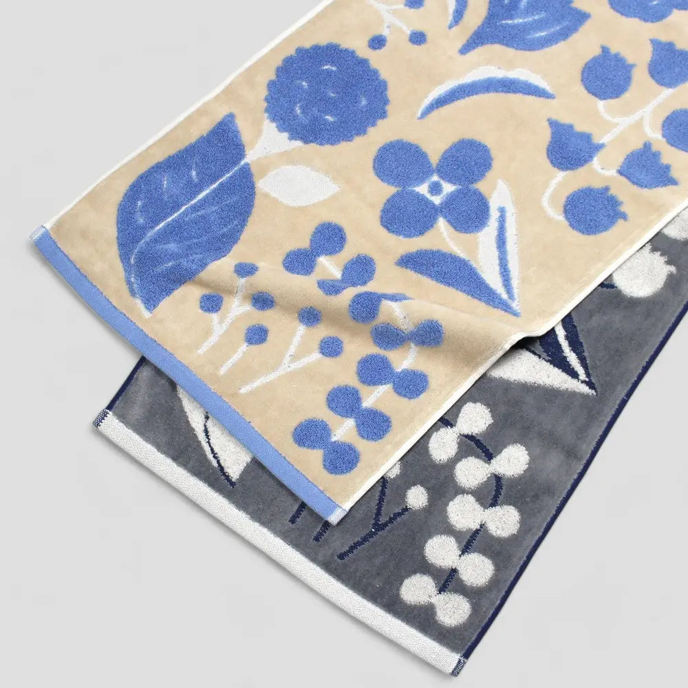 A set of neatly stacked Imabari towels with a floral jacquard pattern in gray and beige colors.