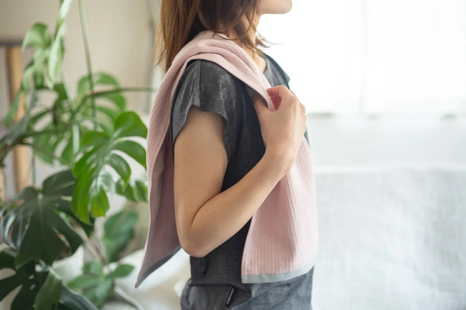 A woman with a sports towel over her shoulders after a workout