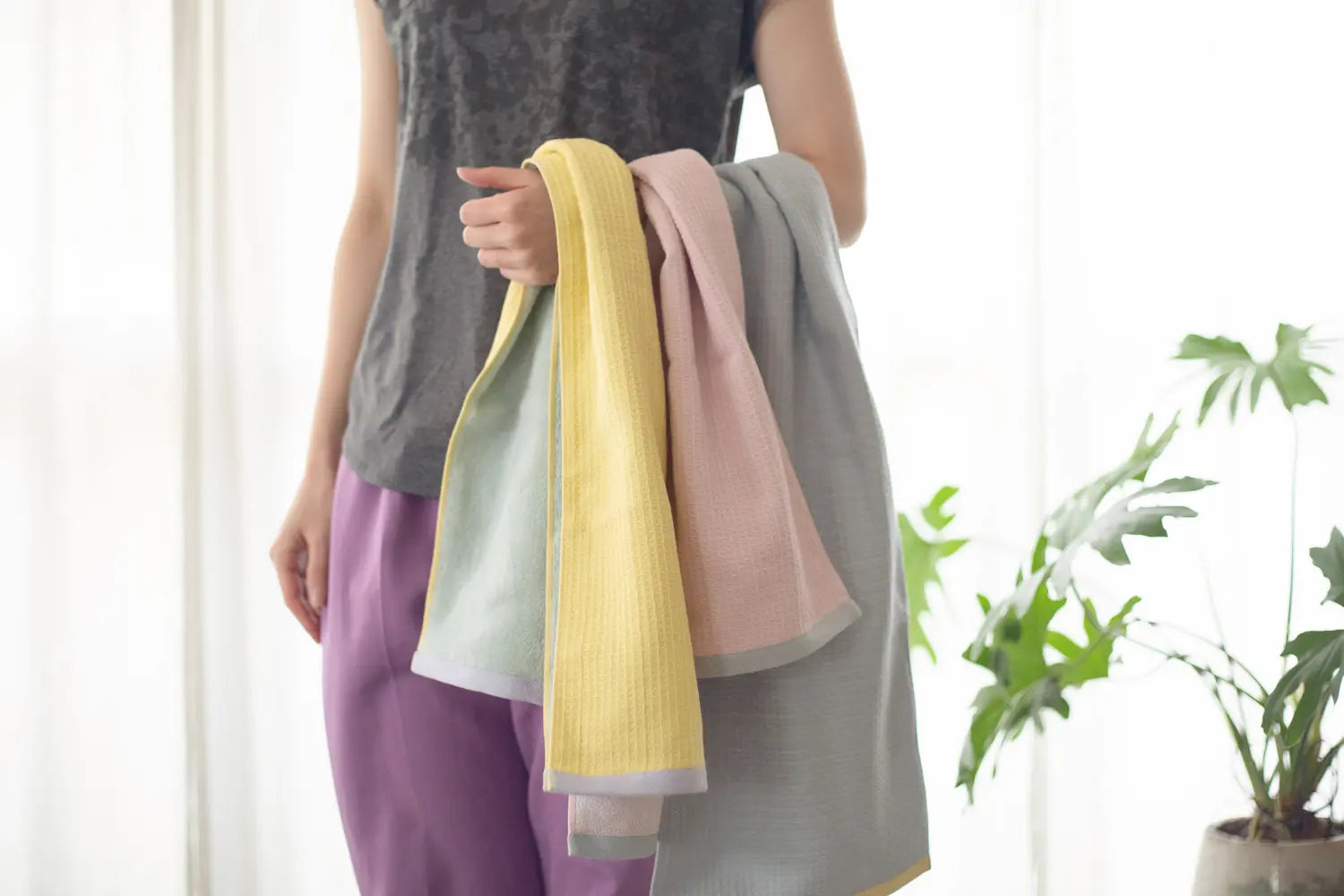 A woman displaying a collection of Imabari sports towels in three colors over her arm.