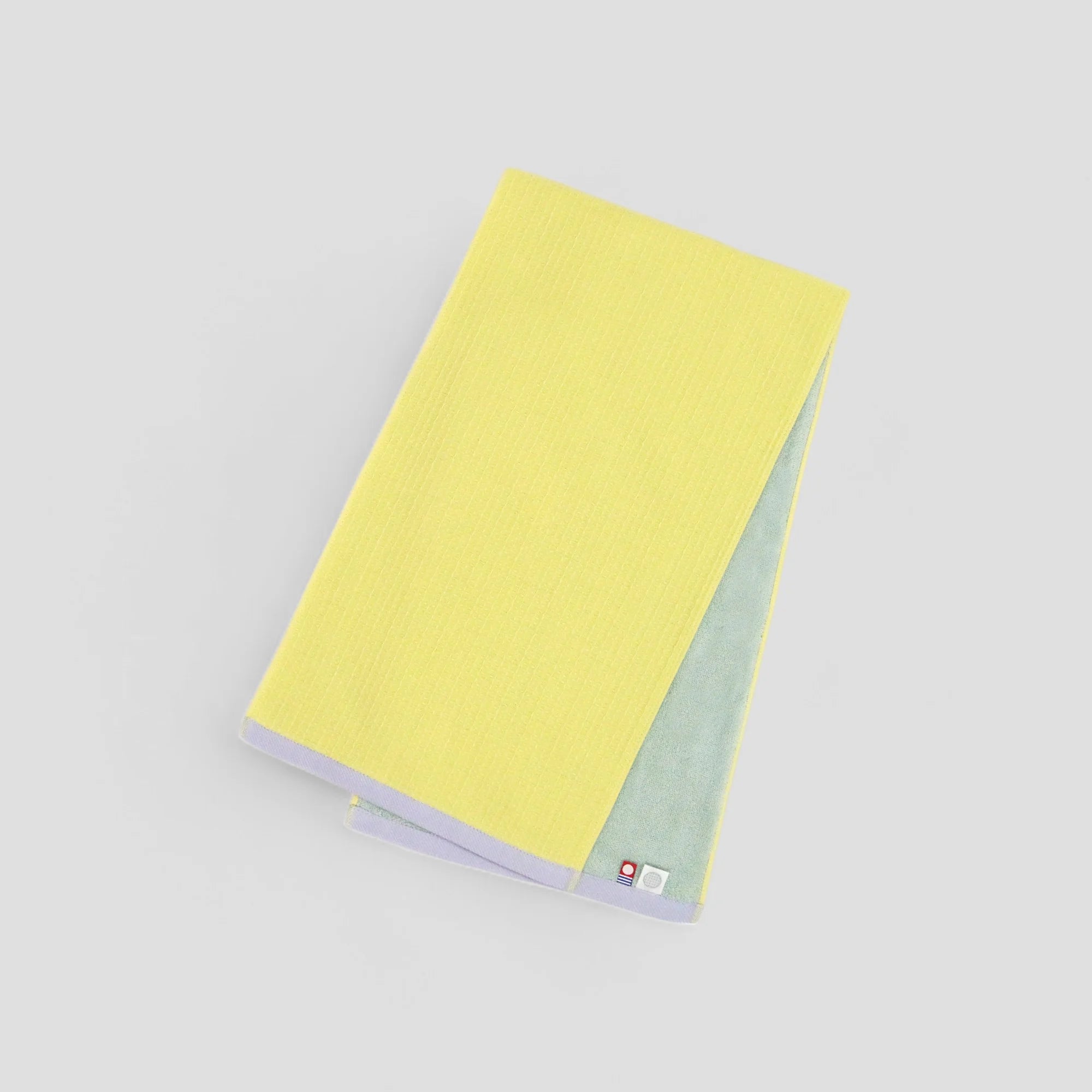 A folded yellow Imabari towel with the brand label visible.