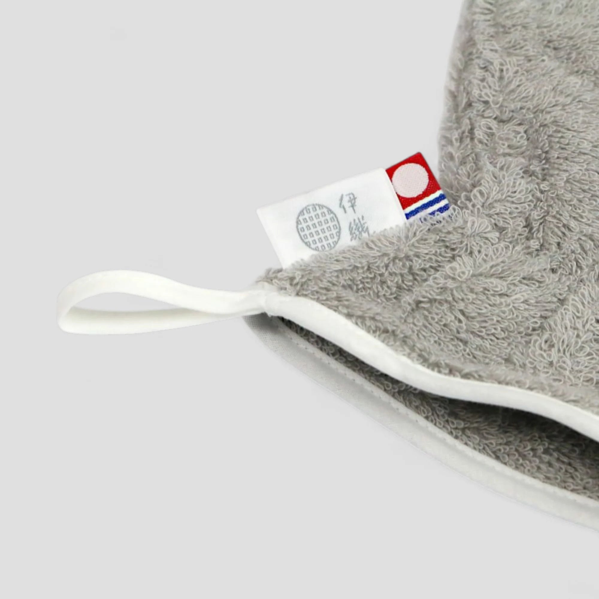 Gray Imabari towel hair-dry-glove with a white brand label on a light gray background