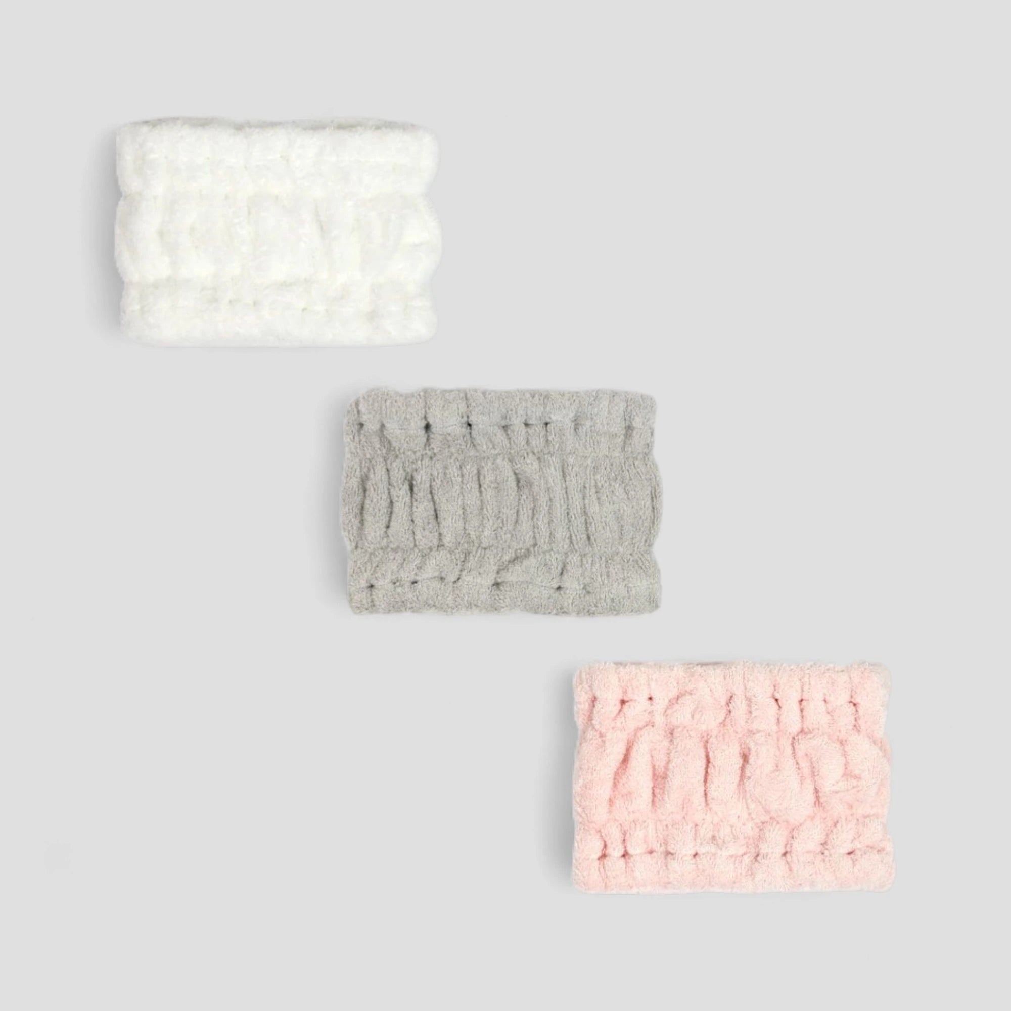Three textured Imabari towel headbands in white, gray, and pink on a light gray background