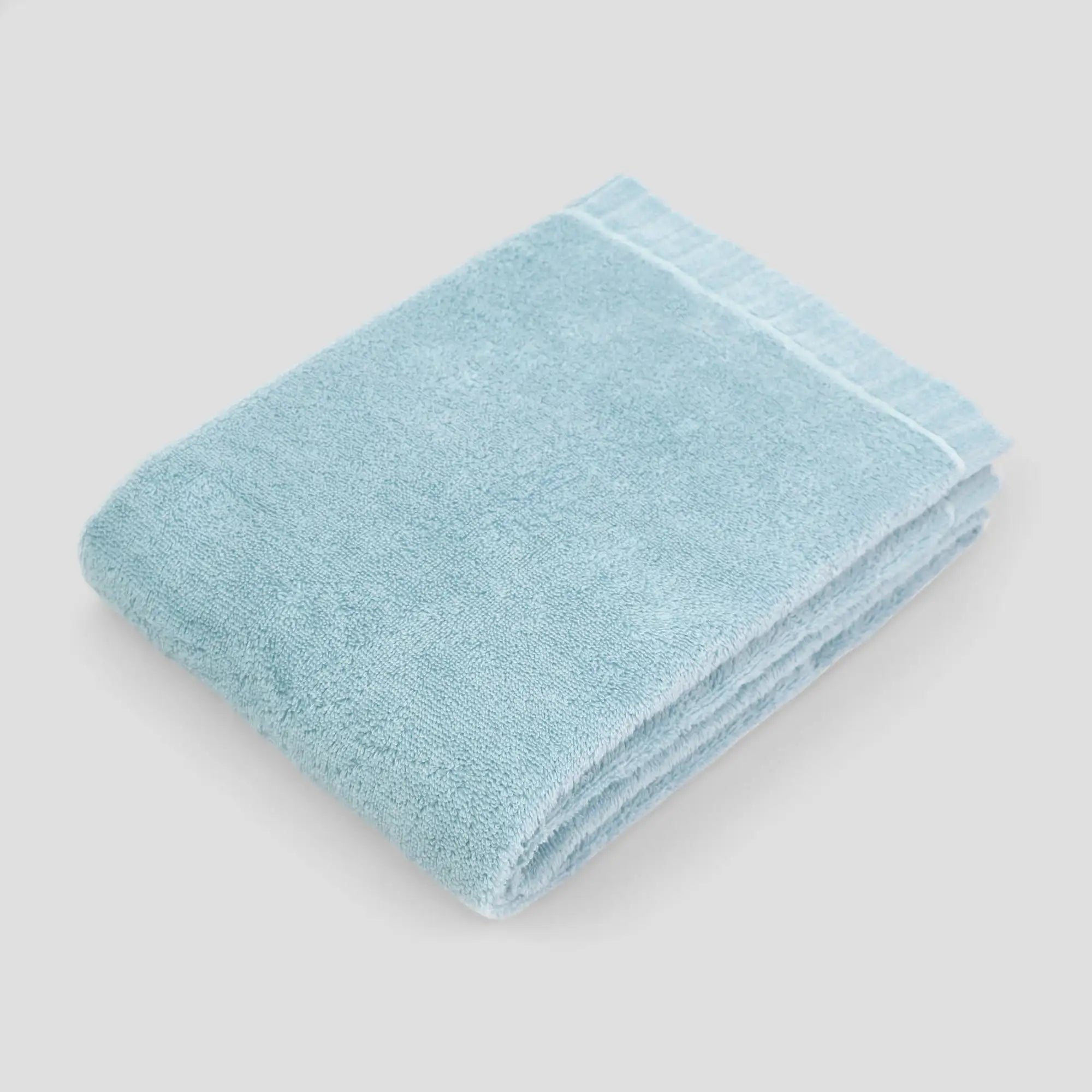 Folded light blue Imabari towel on a light gray background