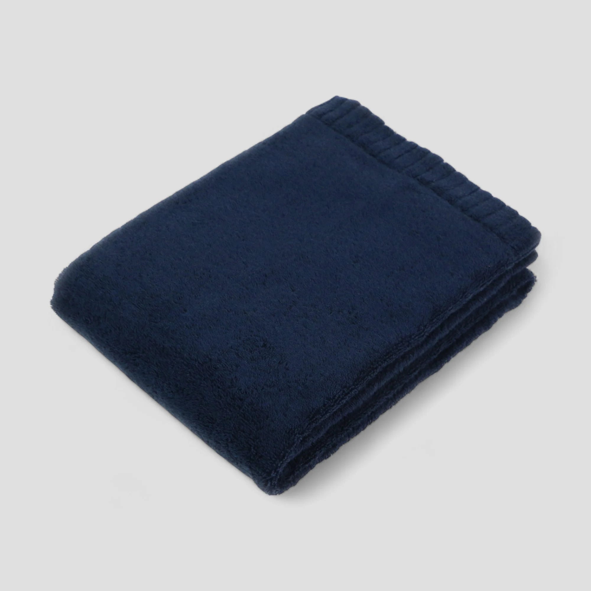 Folded navy blue Imabari towel on a light gray background