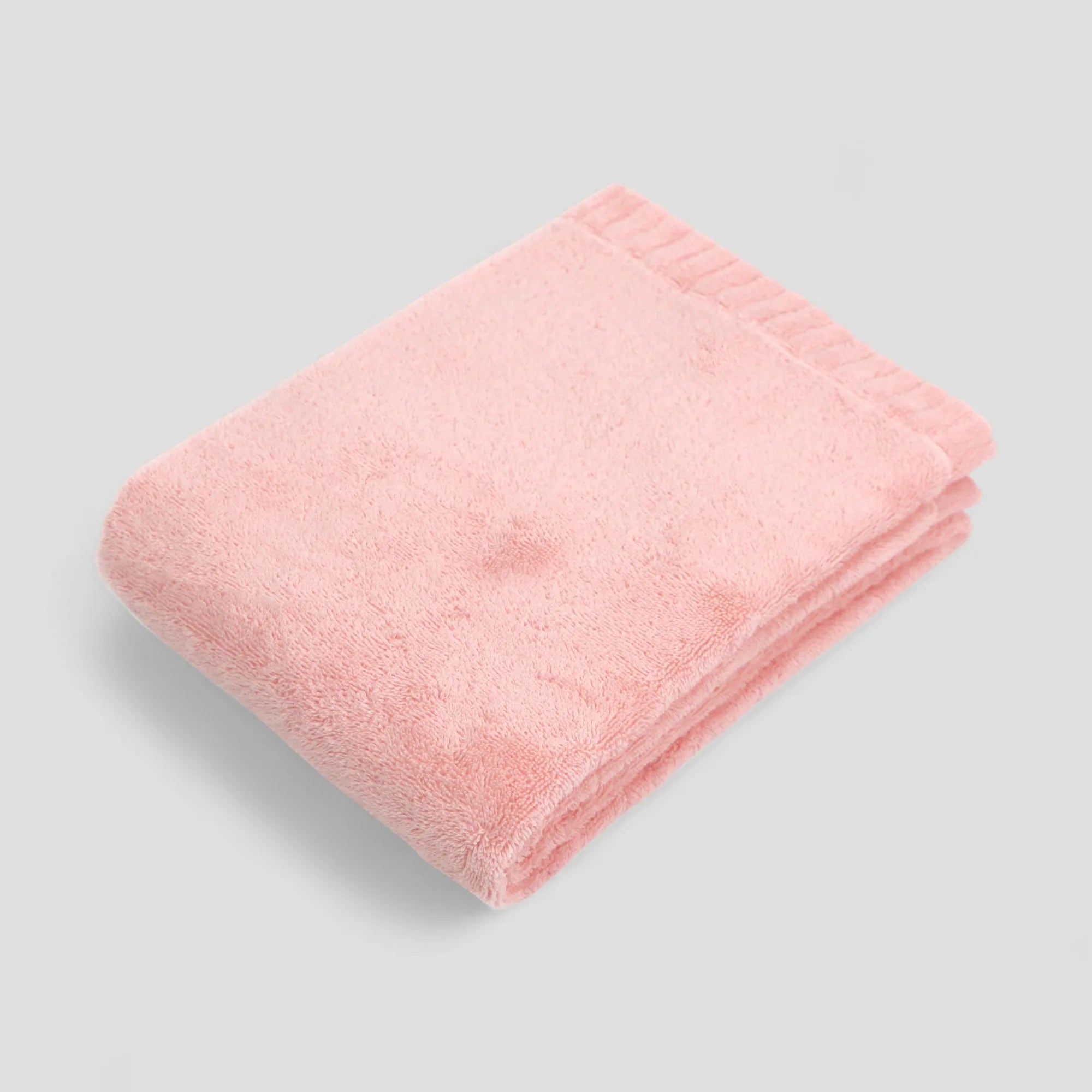 Folded pink Imabari towel on a gray background