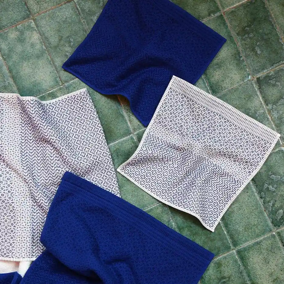 Blue and white Imabari towel with a geometric pattern on a green tiled floor