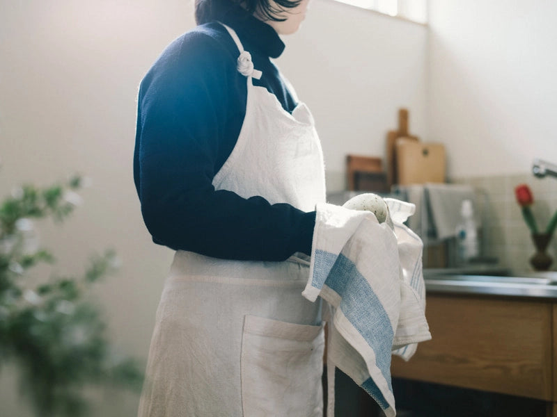 A woman holding Imabari towel kitchen linen in blue line in a kitchen